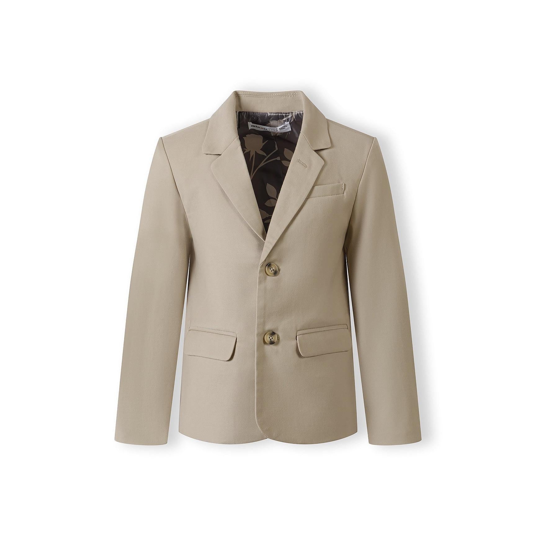 Close-up detail of stone blazer chest pocket showing tailored construction and fabric texture