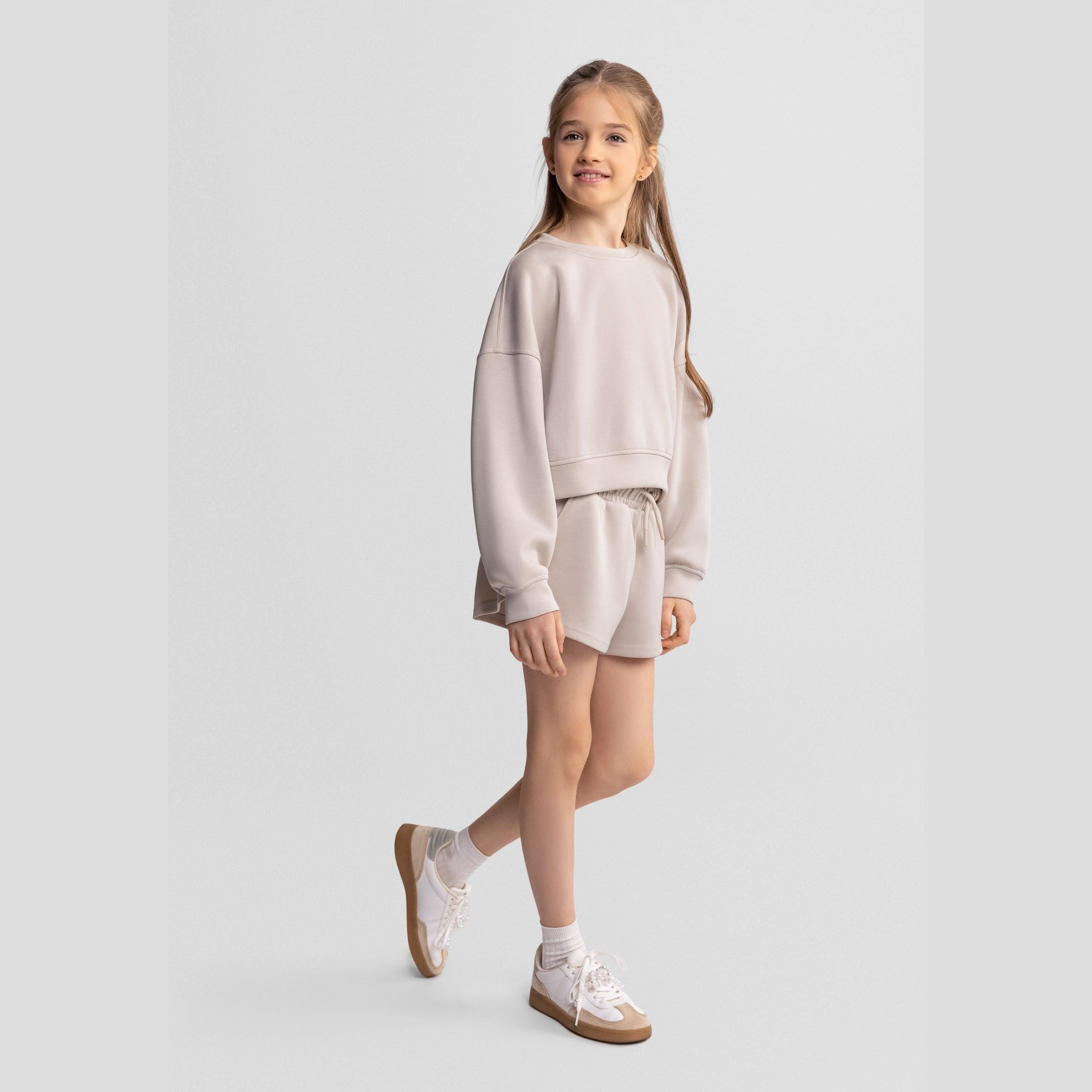 Beige sweatshirt laid flat showing relaxed crew neck design and long sleeves on white background