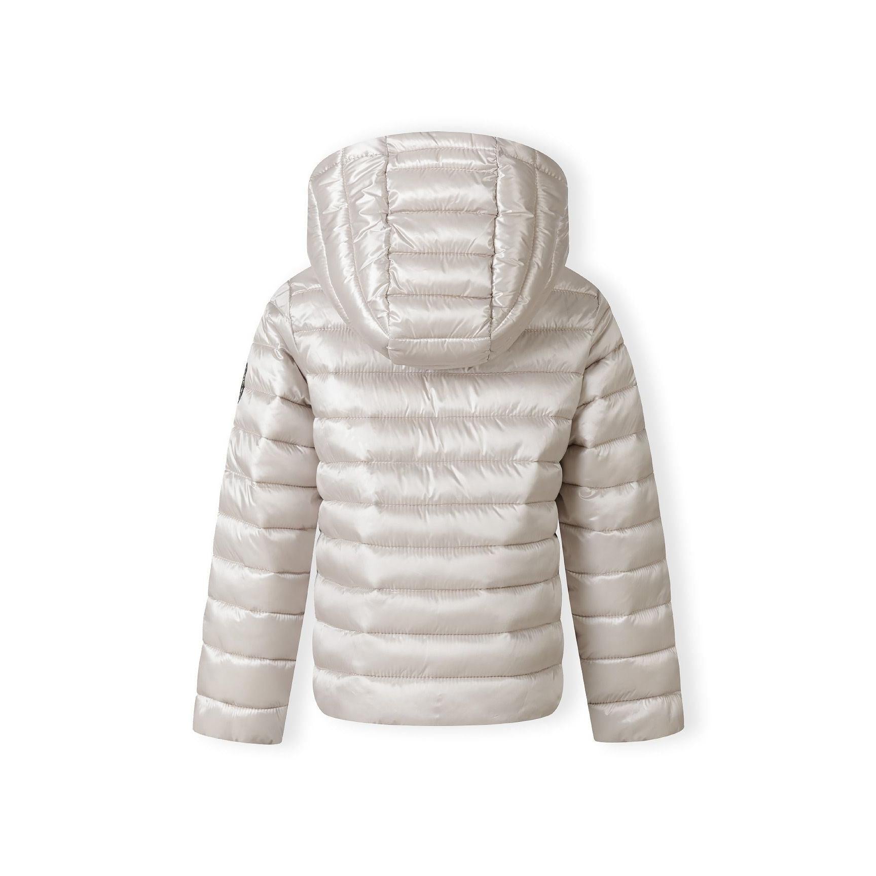 Close-up detail of grey quilted jacket showing circular embroidered patch with heart design and quilted texture