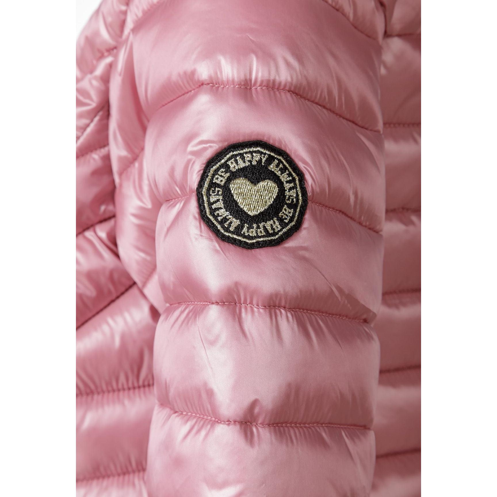 Close-up detail of circular embroidered heart badge on pink quilted jacket sleeve