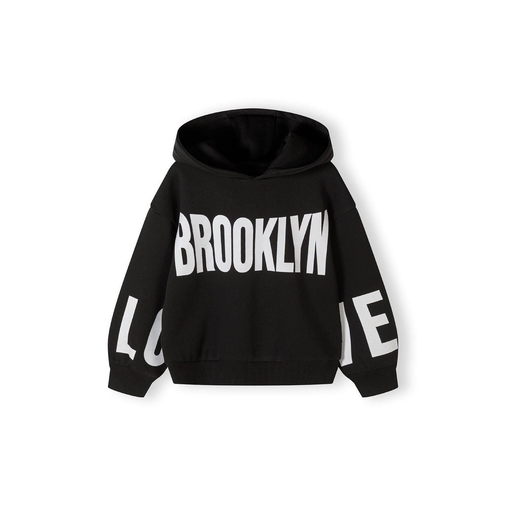 Close-up detail of black tracksuit joggers showing ribbed waistband and white text print on leg