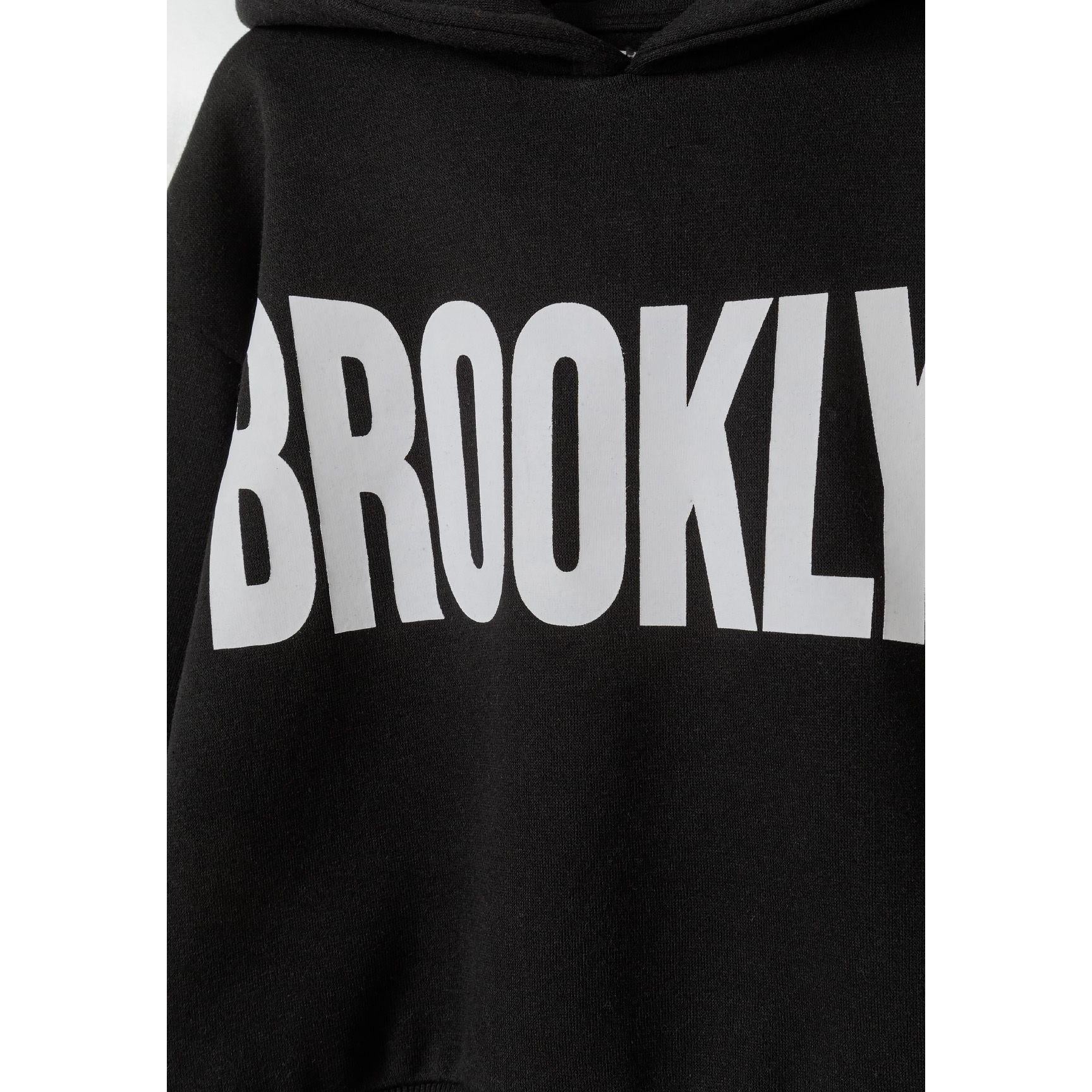 Close-up detail of black tracksuit joggers showing ribbed waistband and white text print on leg