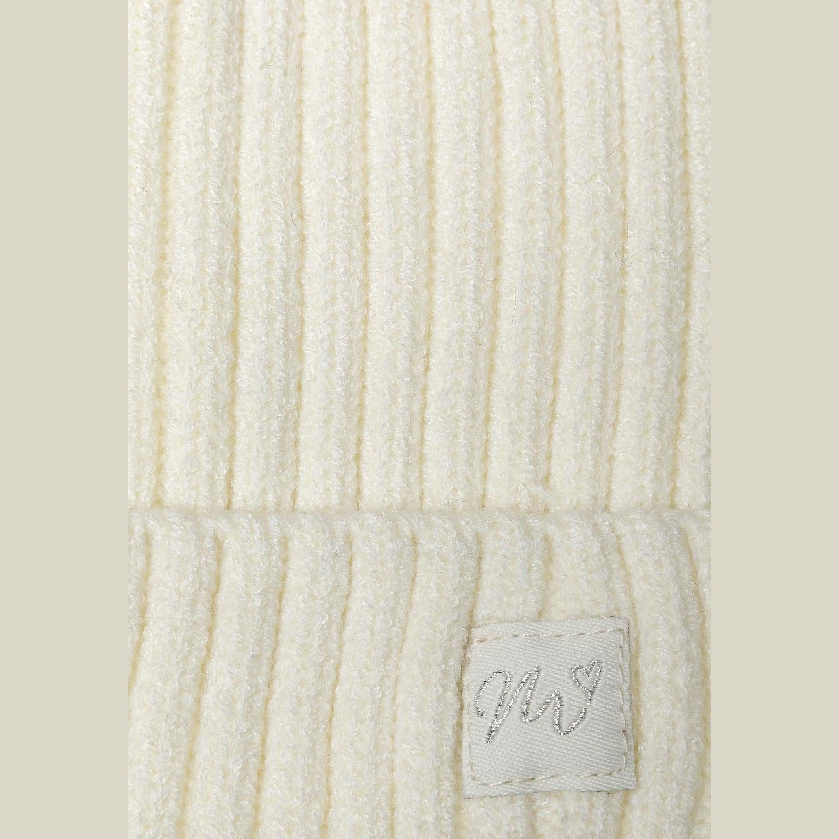 Close-up detail of cream ribbed knit texture showing the lurex badge with script lettering on light background