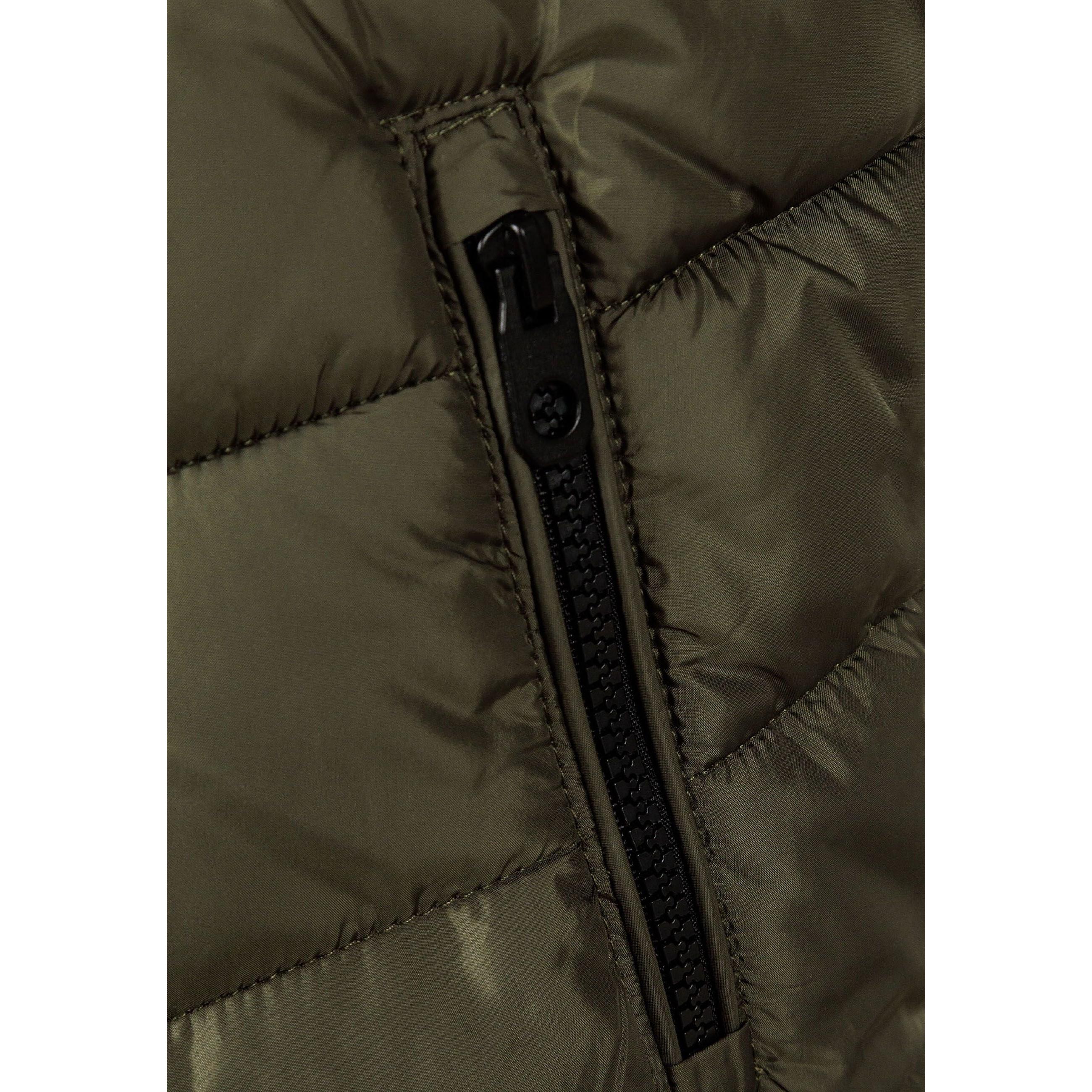 Close-up detail of black circular logo patch on khaki padded fabric with quilted stitching pattern