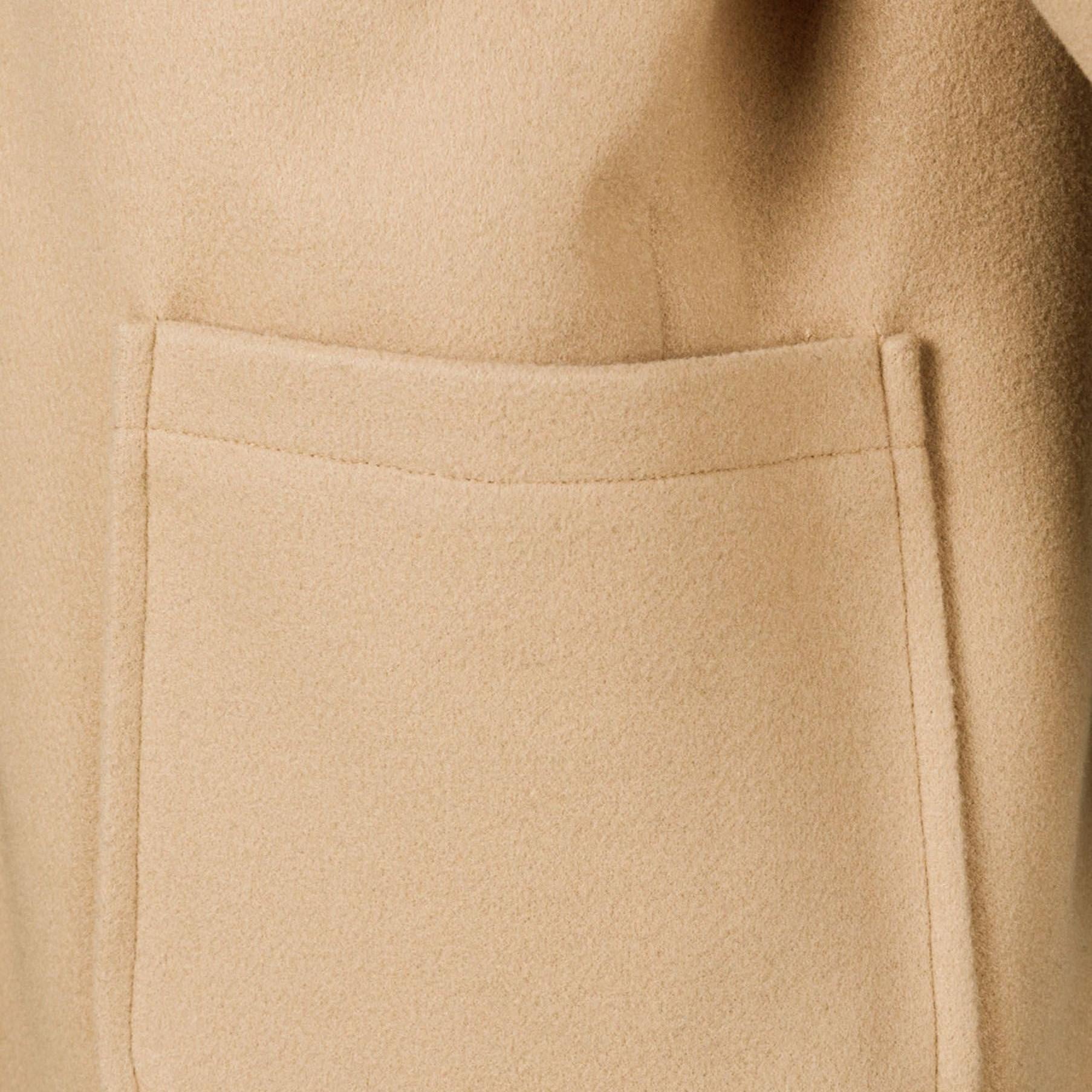 Close-up detail of beige winter coat front pocket showing stitching and fabric texture