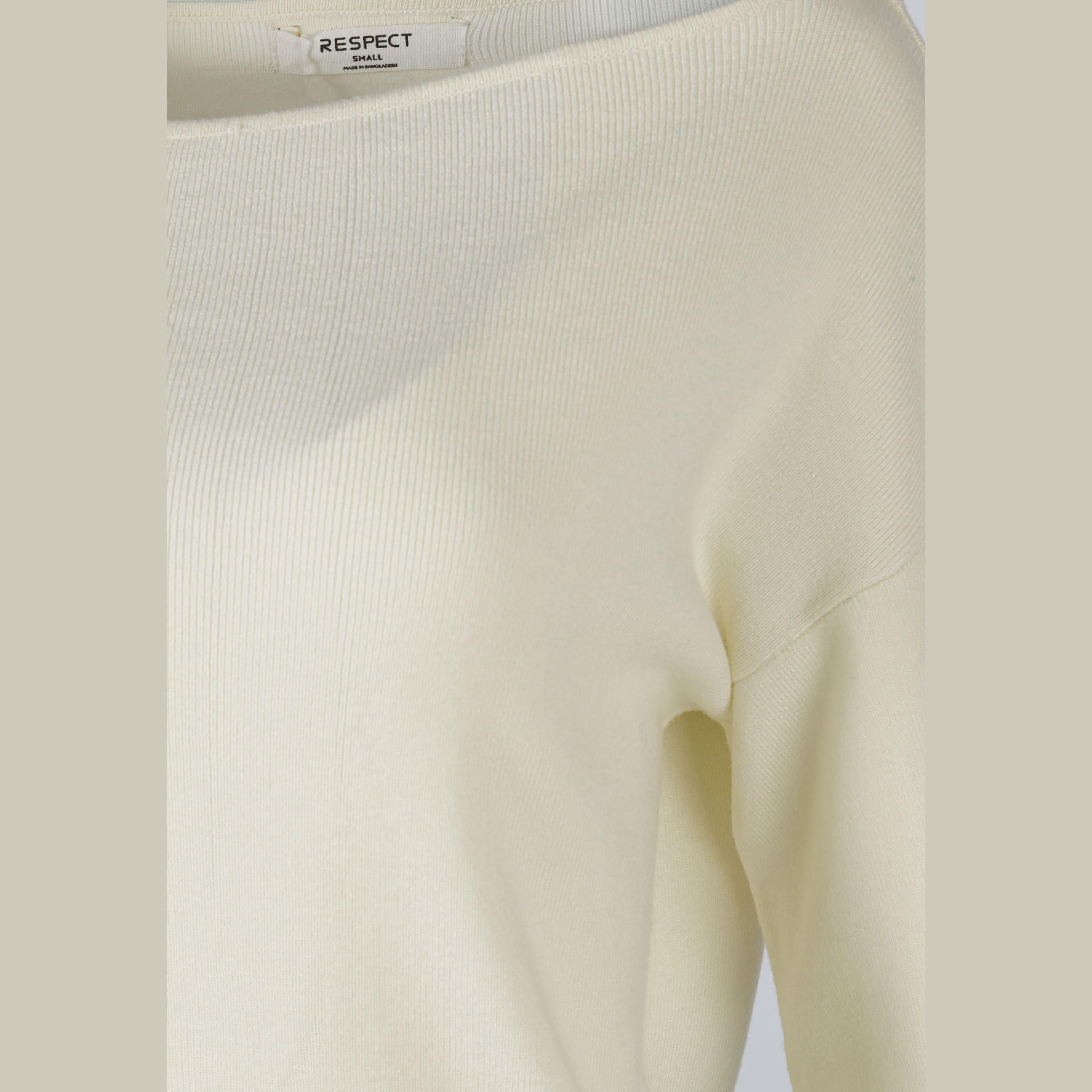 Close-up detail of cream jumper showing RESPECT brand label and textured knit fabric construction