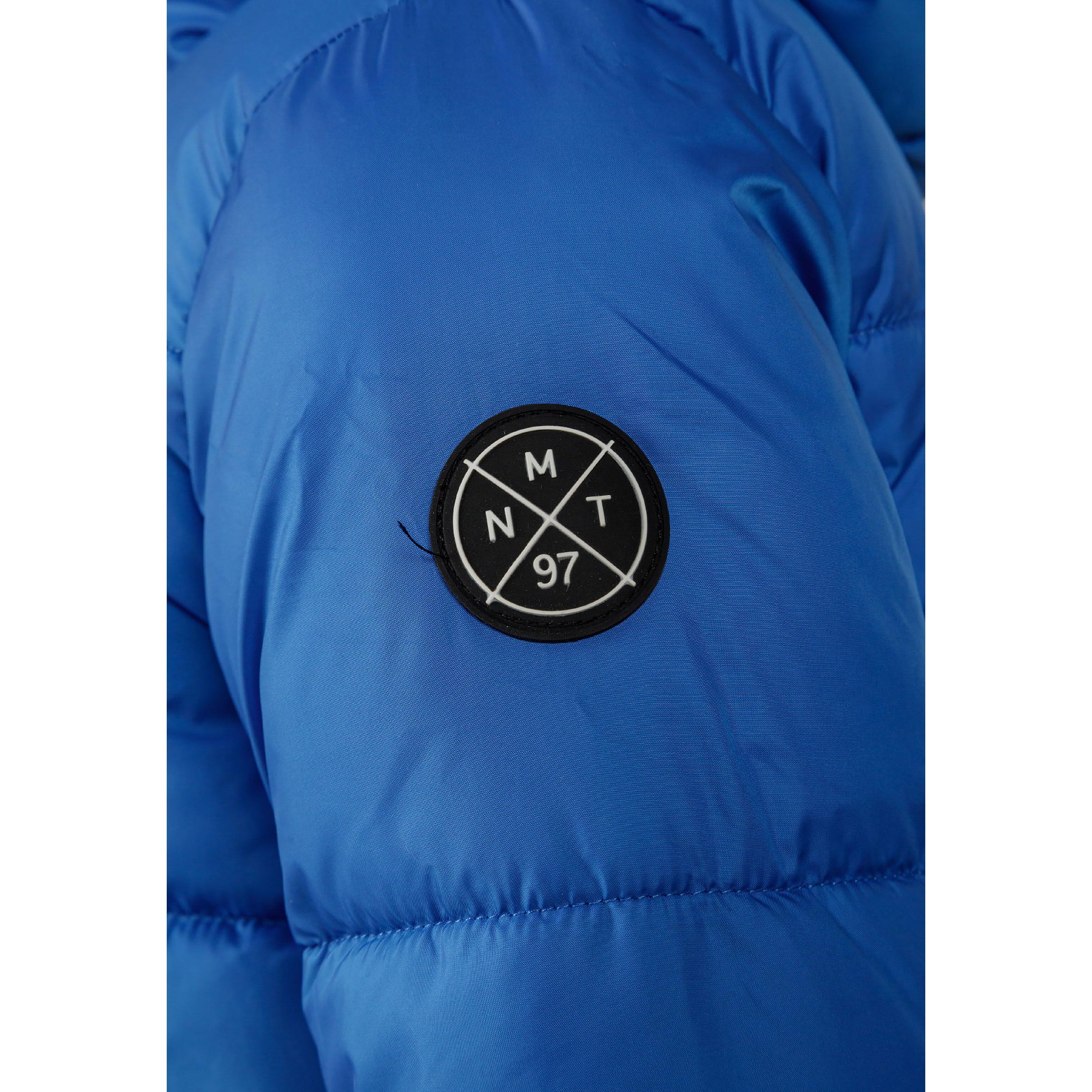 Close-up detail of cobalt blue jacket sleeve showing circular black patch with white crossed lines and letters M, N, T, 97