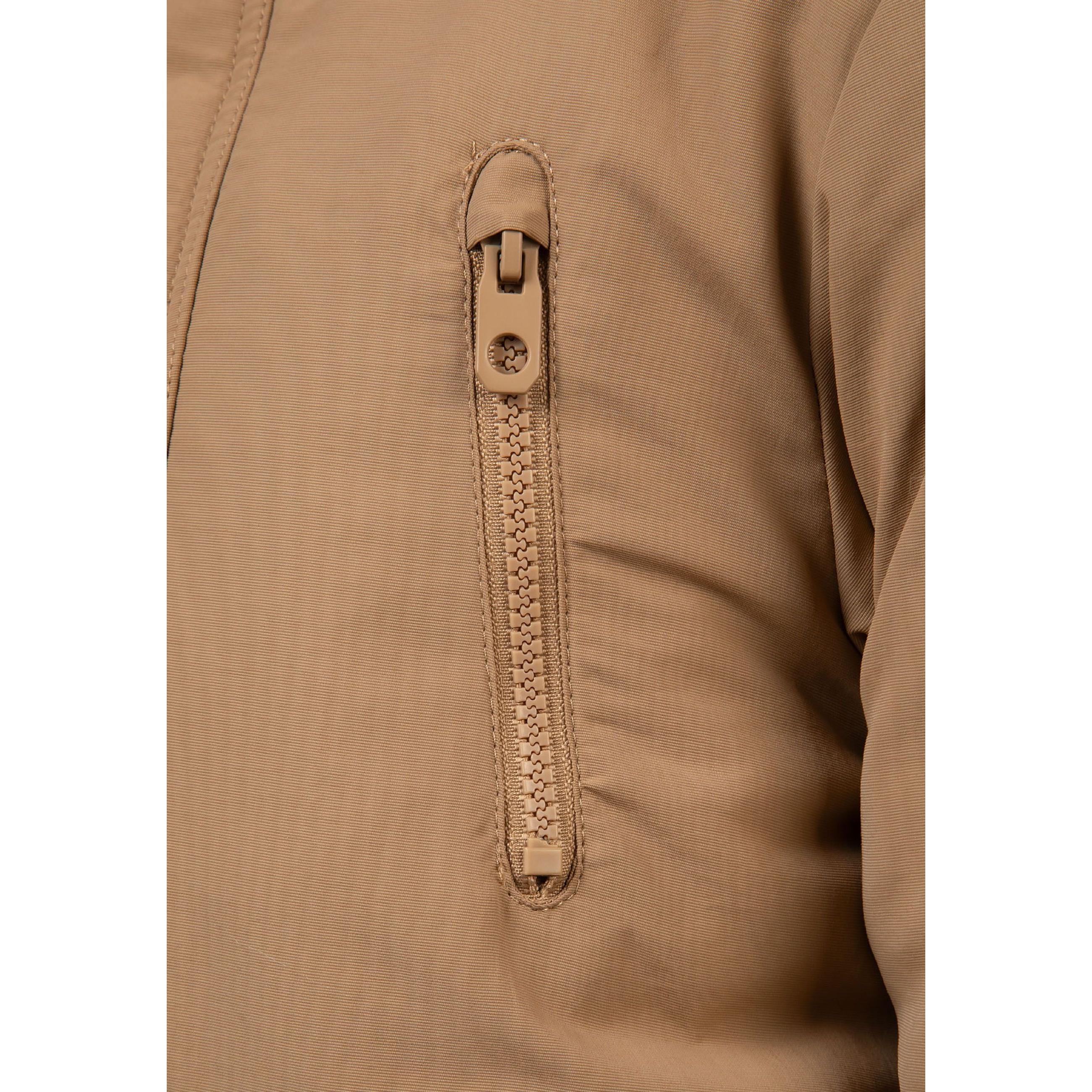 Close-up detail of circular black MTN 97 logo badge on beige parka fabric