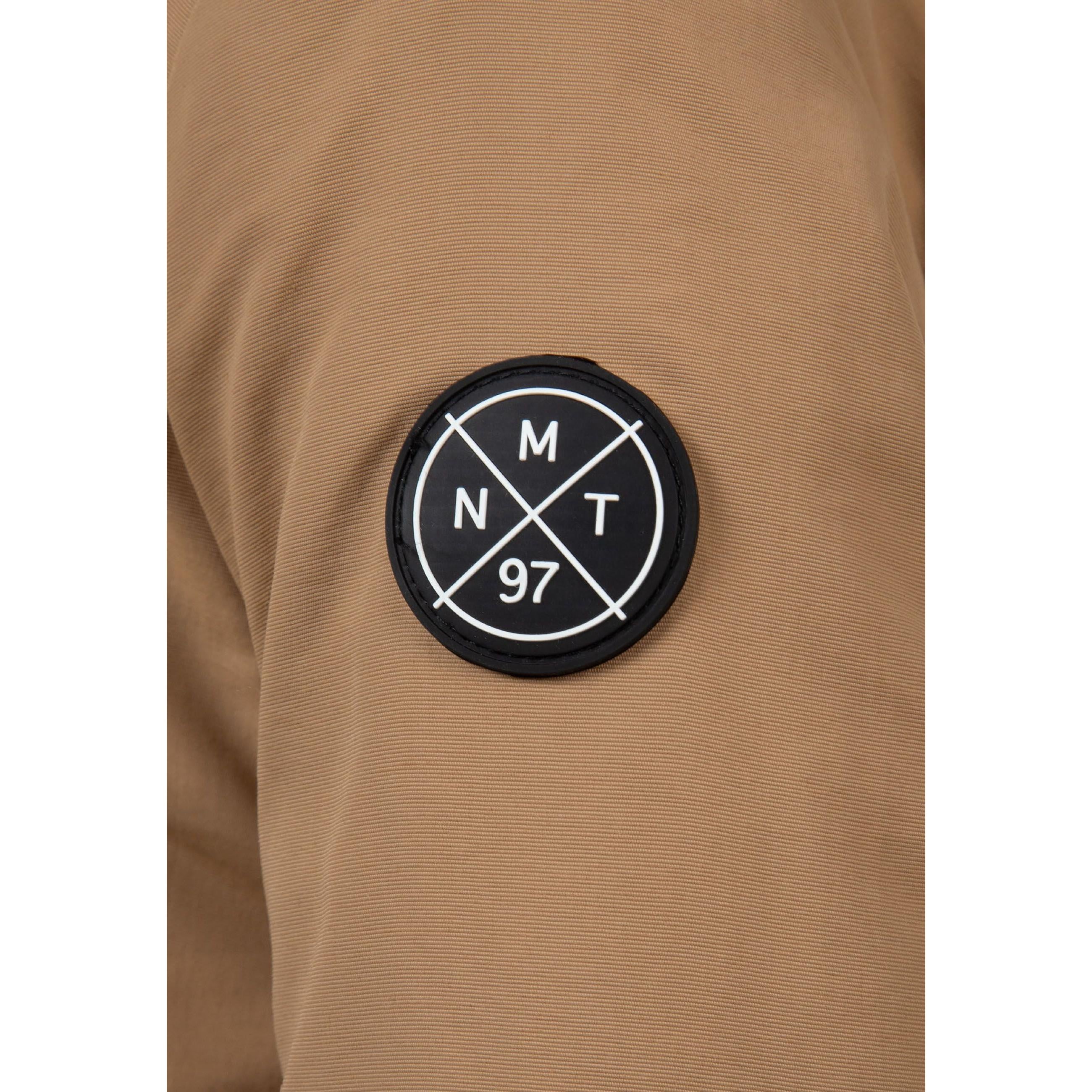 Close-up detail of circular black MTN 97 logo badge on beige parka fabric