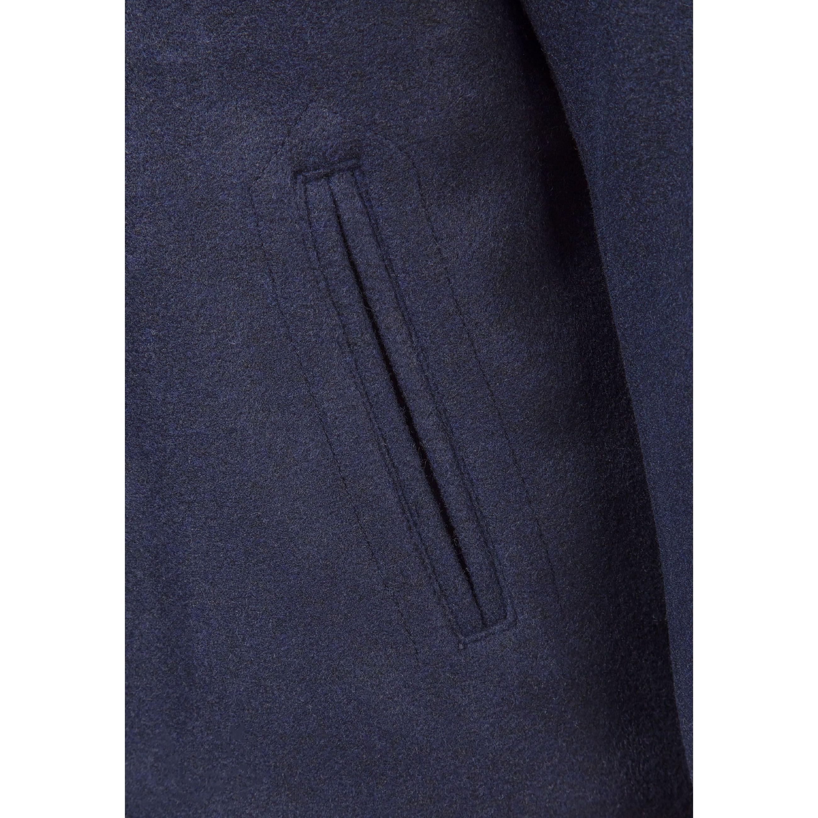 Close-up detail of navy coat pocket showing welt pocket construction and quality fabric texture