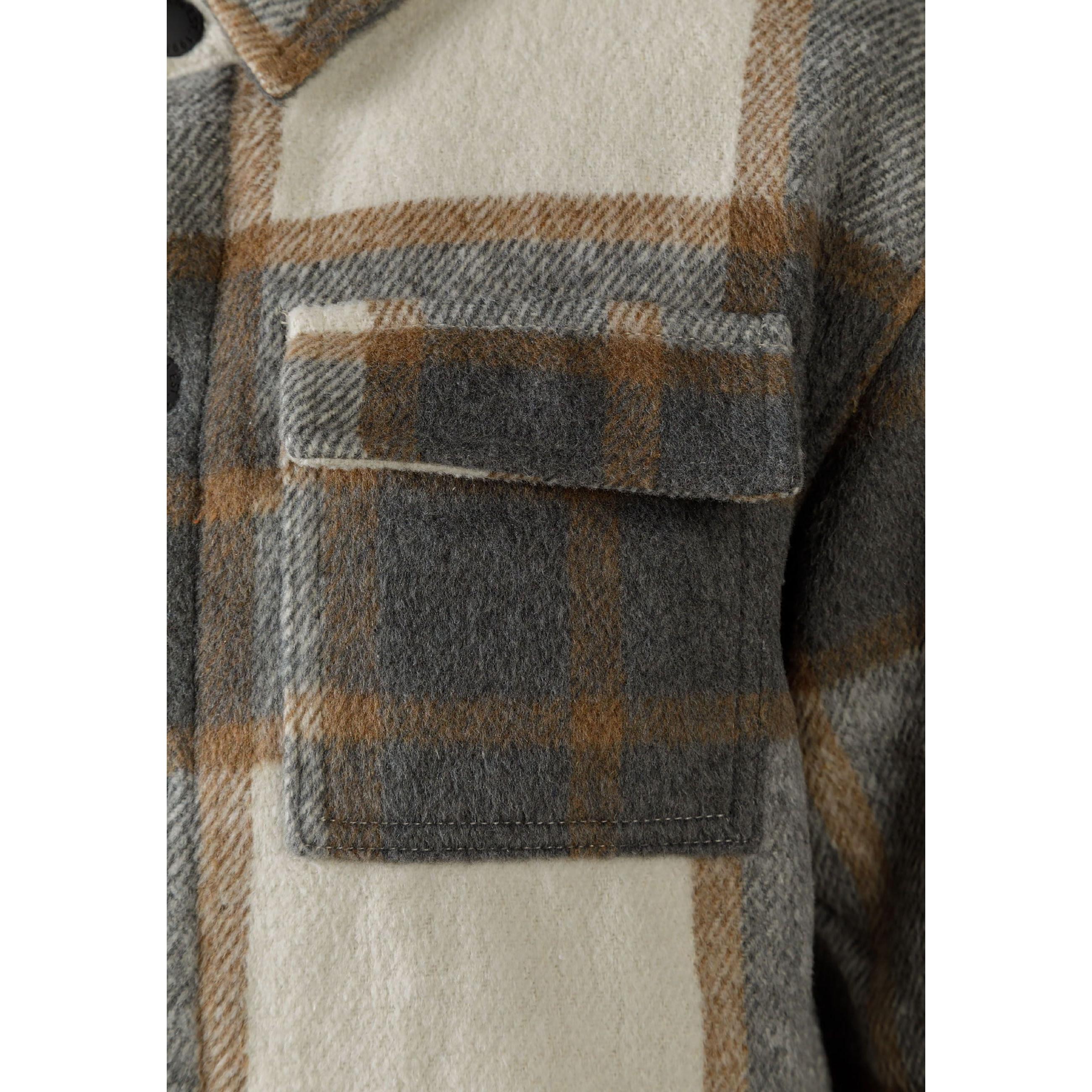 Close-up detail of grey check padded shirt jacket chest pocket with button flap closure and wool blend fabric texture