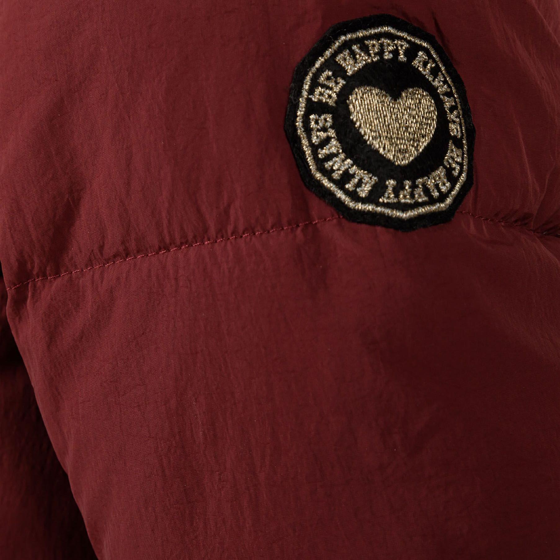 Close-up detail of burgundy quilted fabric showing diagonal stitching pattern and front pocket with matching trim