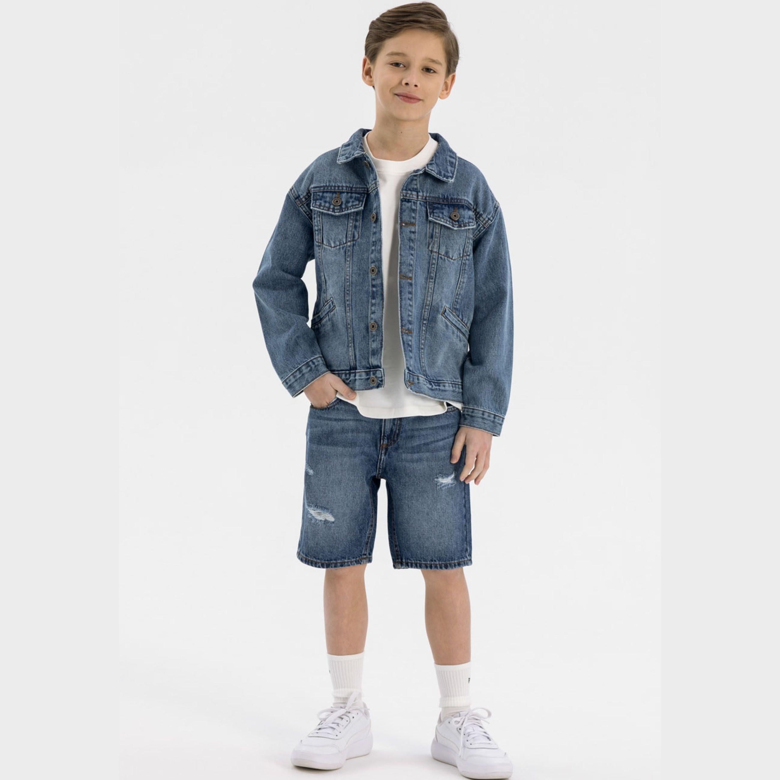 Boy wearing navy denim jacket with white t-shirt and denim shorts, standing against white background, front view showing classic button closure and chest pockets