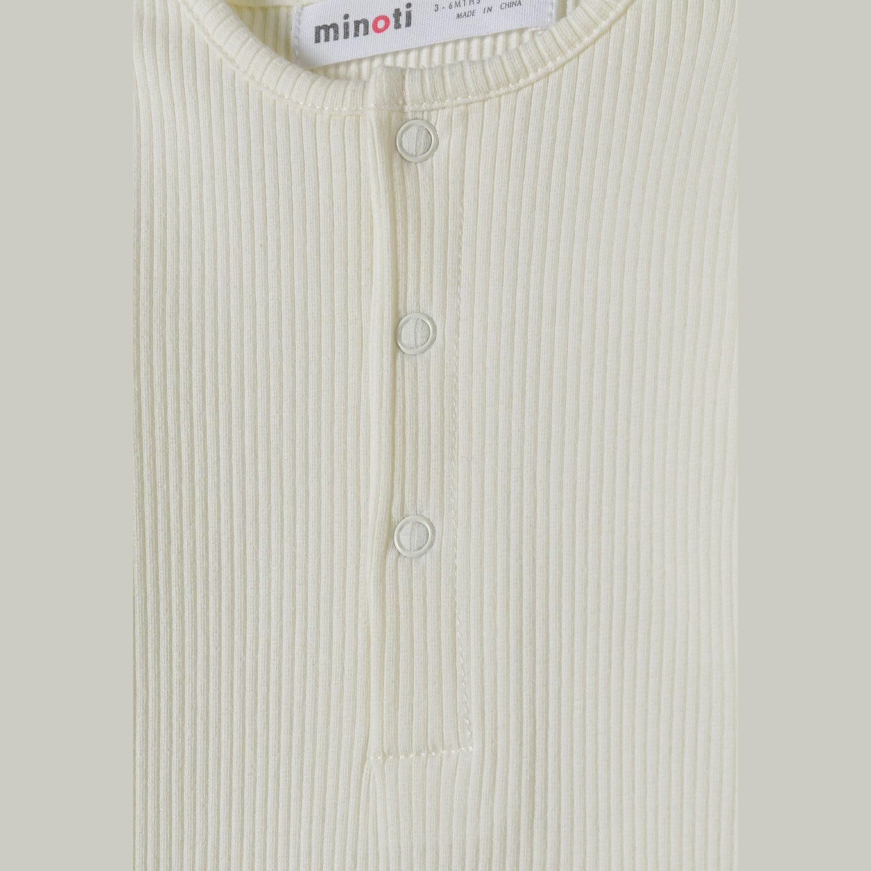 Close-up detail of cream ribbed romper showing Minoti brand label and snap button closure system at neckline