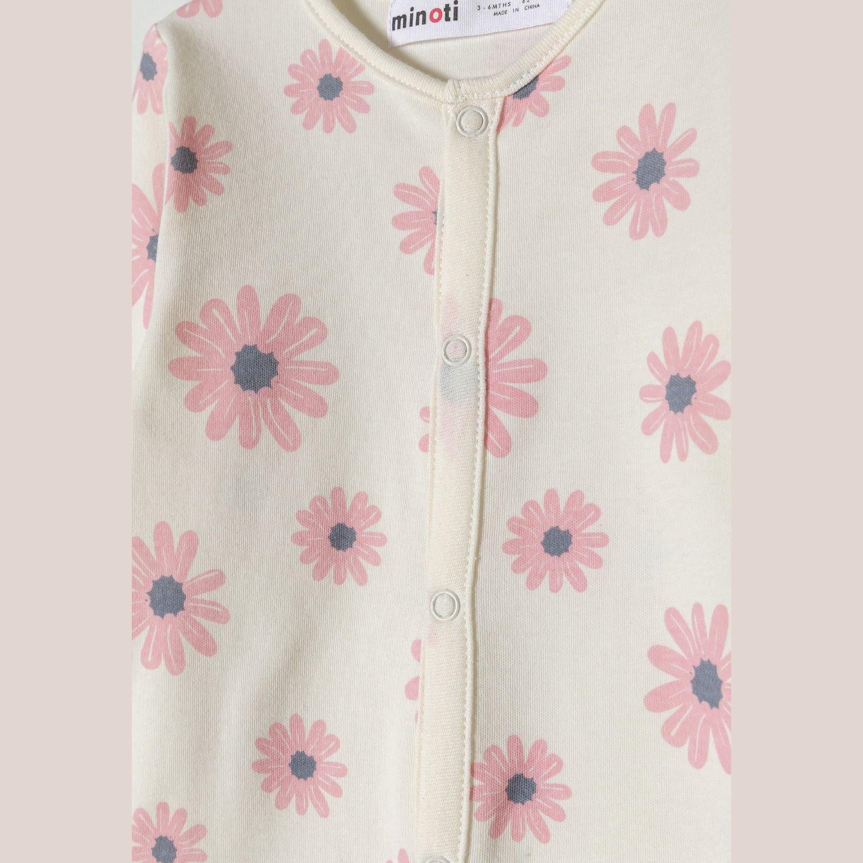 Close-up detail of pink sleepsuit with Minoti label showing white elephant motif with colorful flowers on chest area
