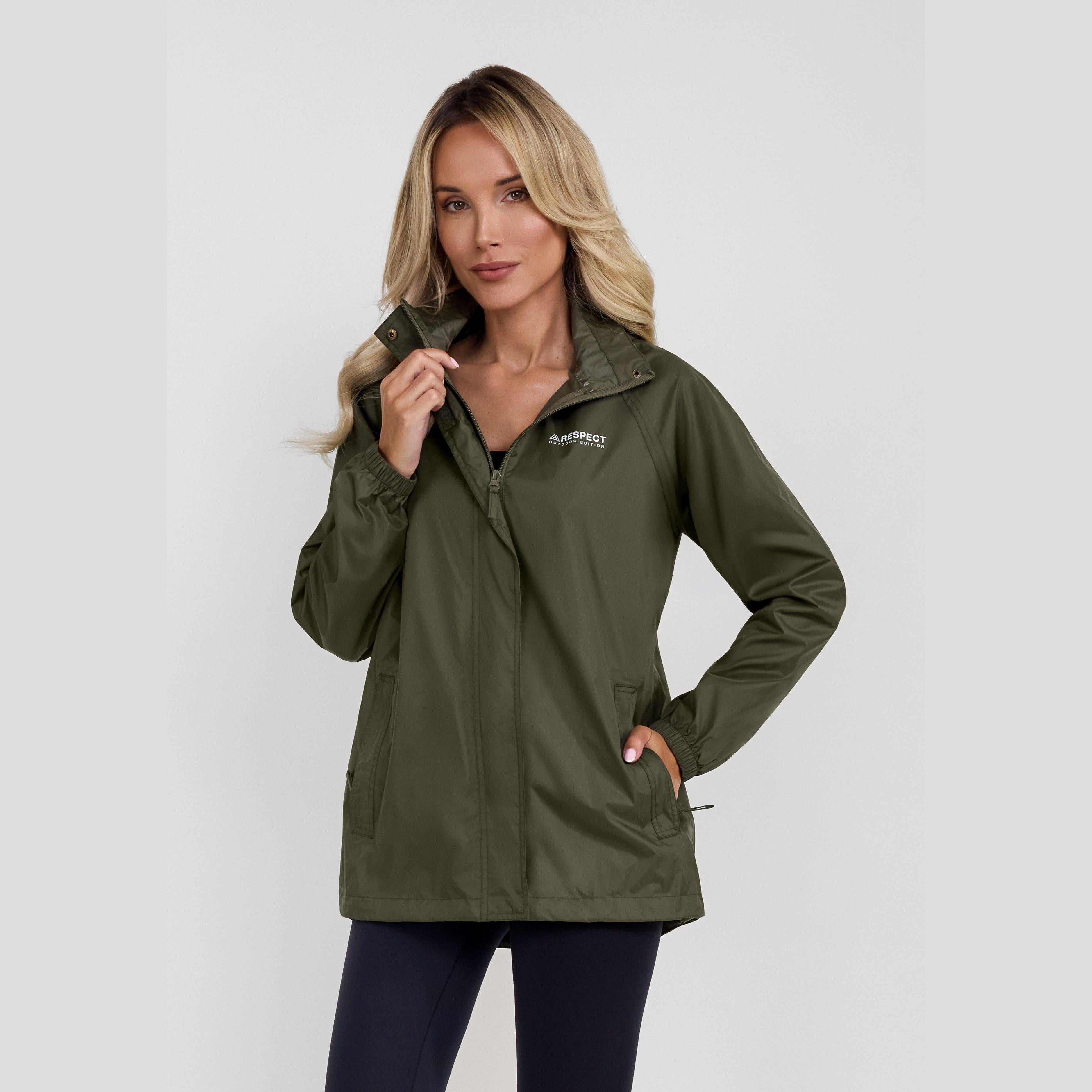 Woman wearing khaki waterproof jacket with hood up against white studio background, blonde hair, showing front view with protective zip closure