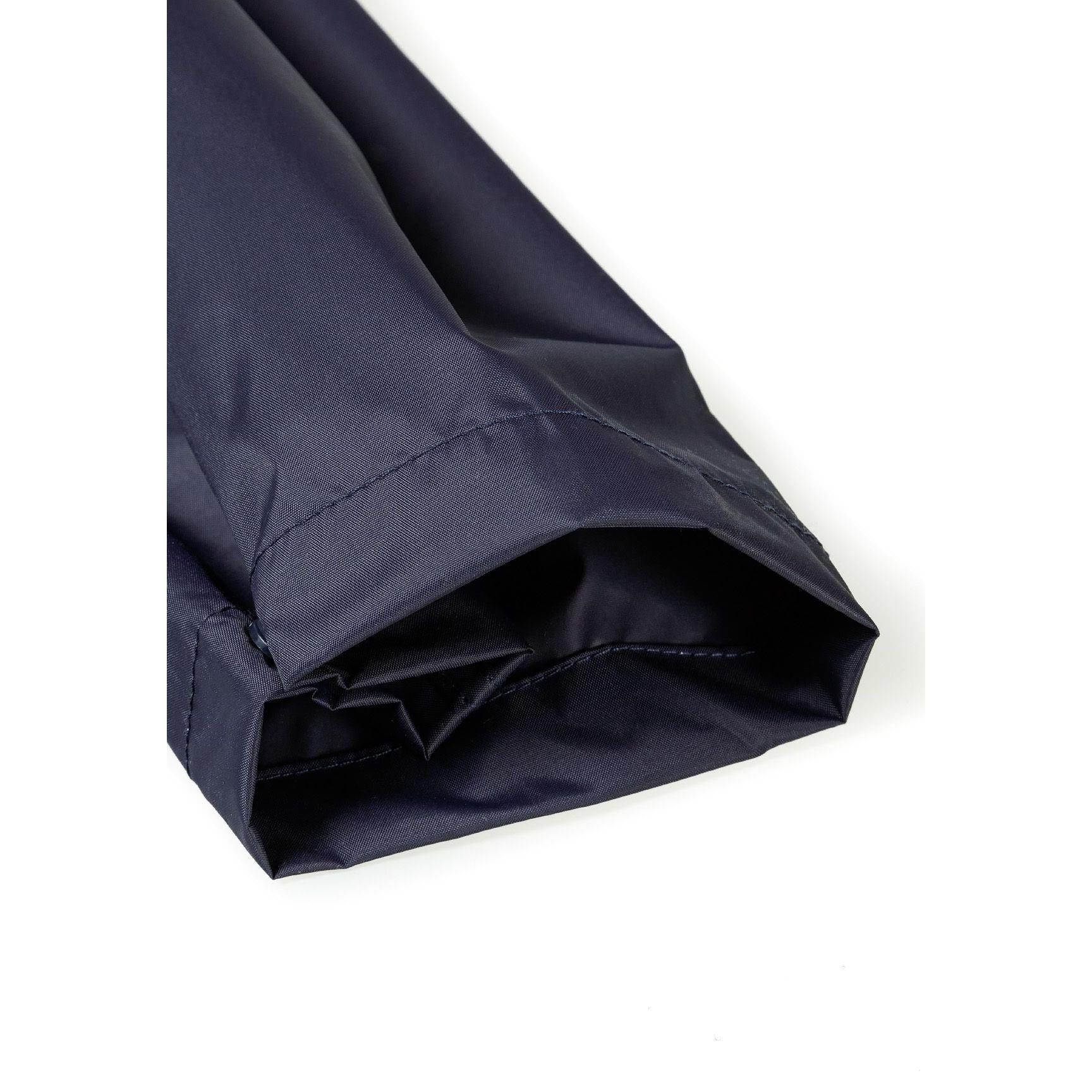 Close-up detail of navy waterproof overpants showing elasticated waistband and packaway fabric construction