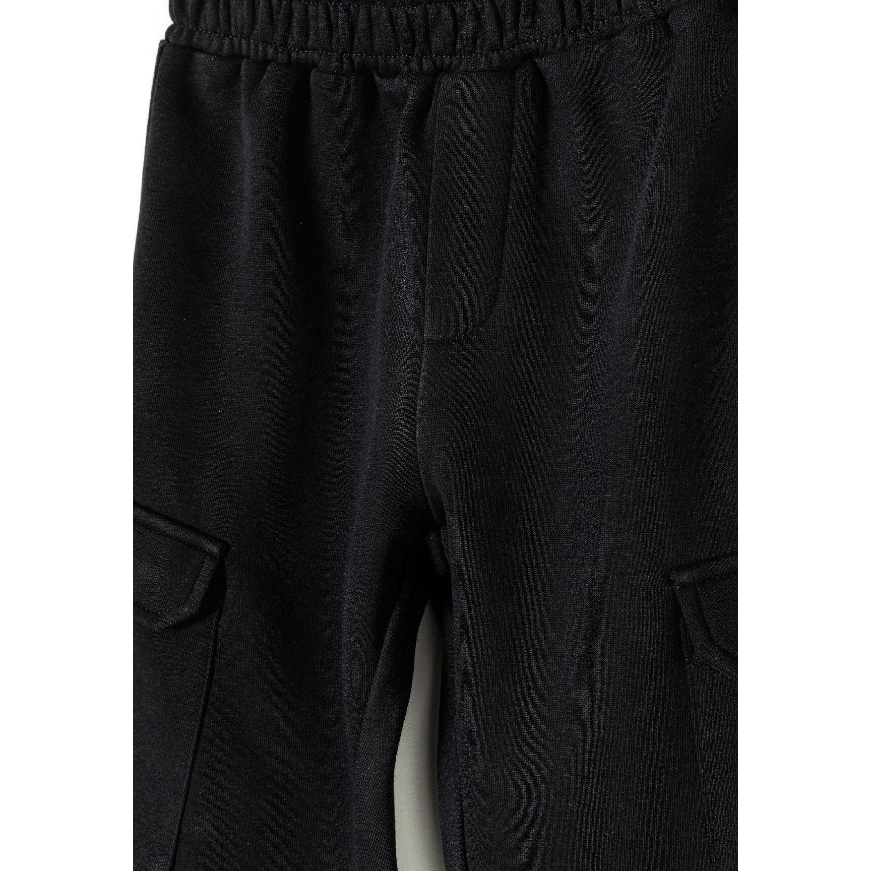 Close-up detail of black fleece cargo joggers showing elasticated waistband with drawstring and cargo pocket construction