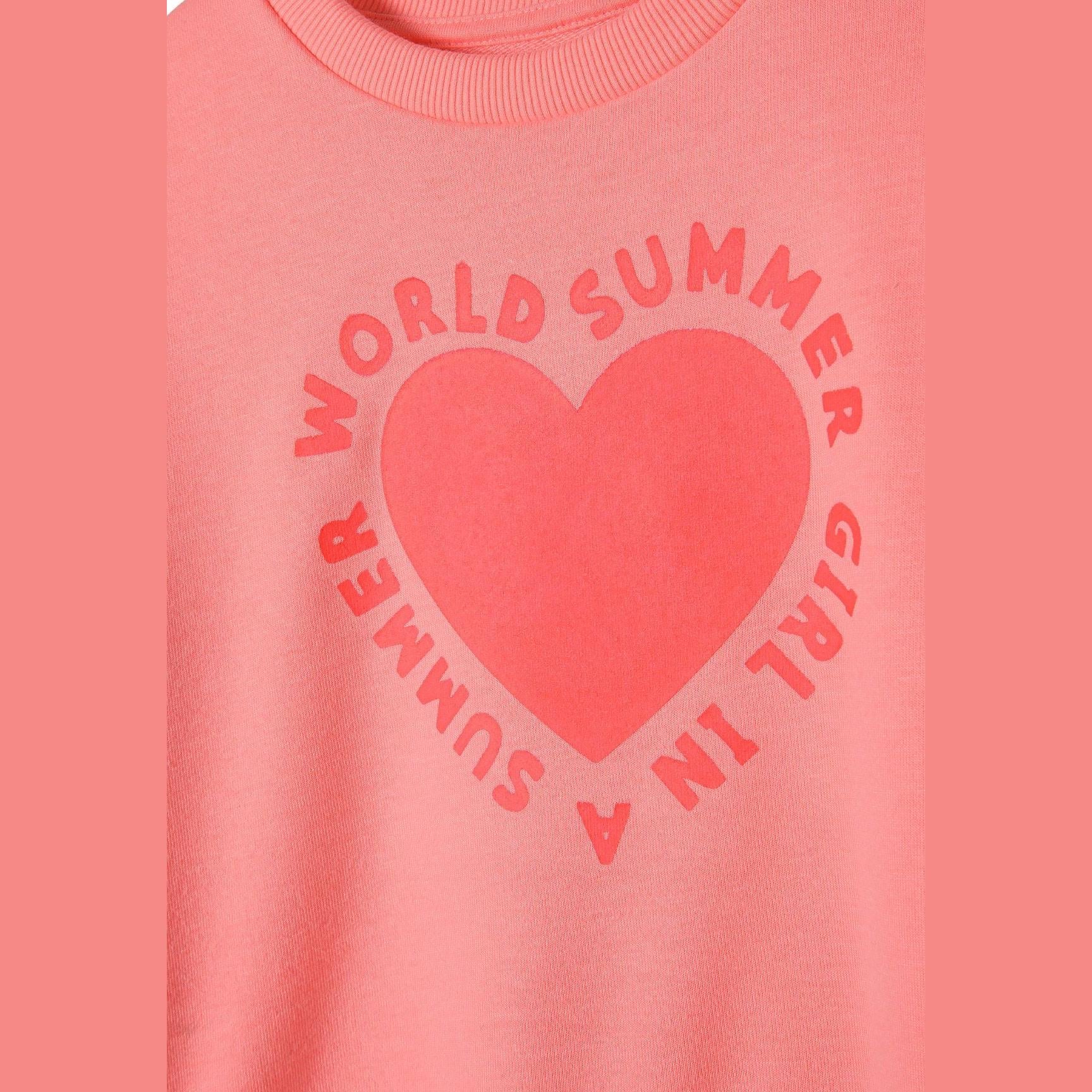 Close-up detail of coral sweatshirt showing heart print with 'World Summer Girl' text in circular arrangement around red heart design