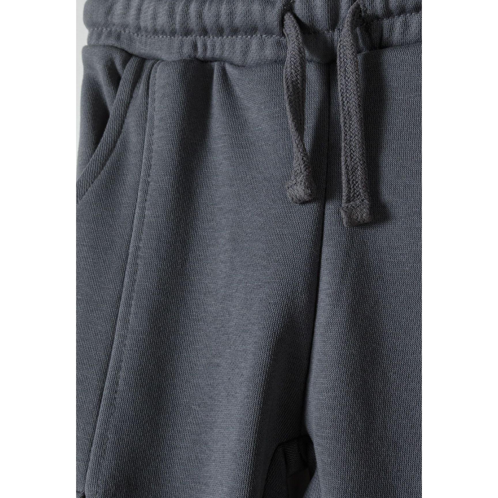 Close-up detail of grey joggers waistband showing drawstring ties and elasticated fabric construction with ribbed texture