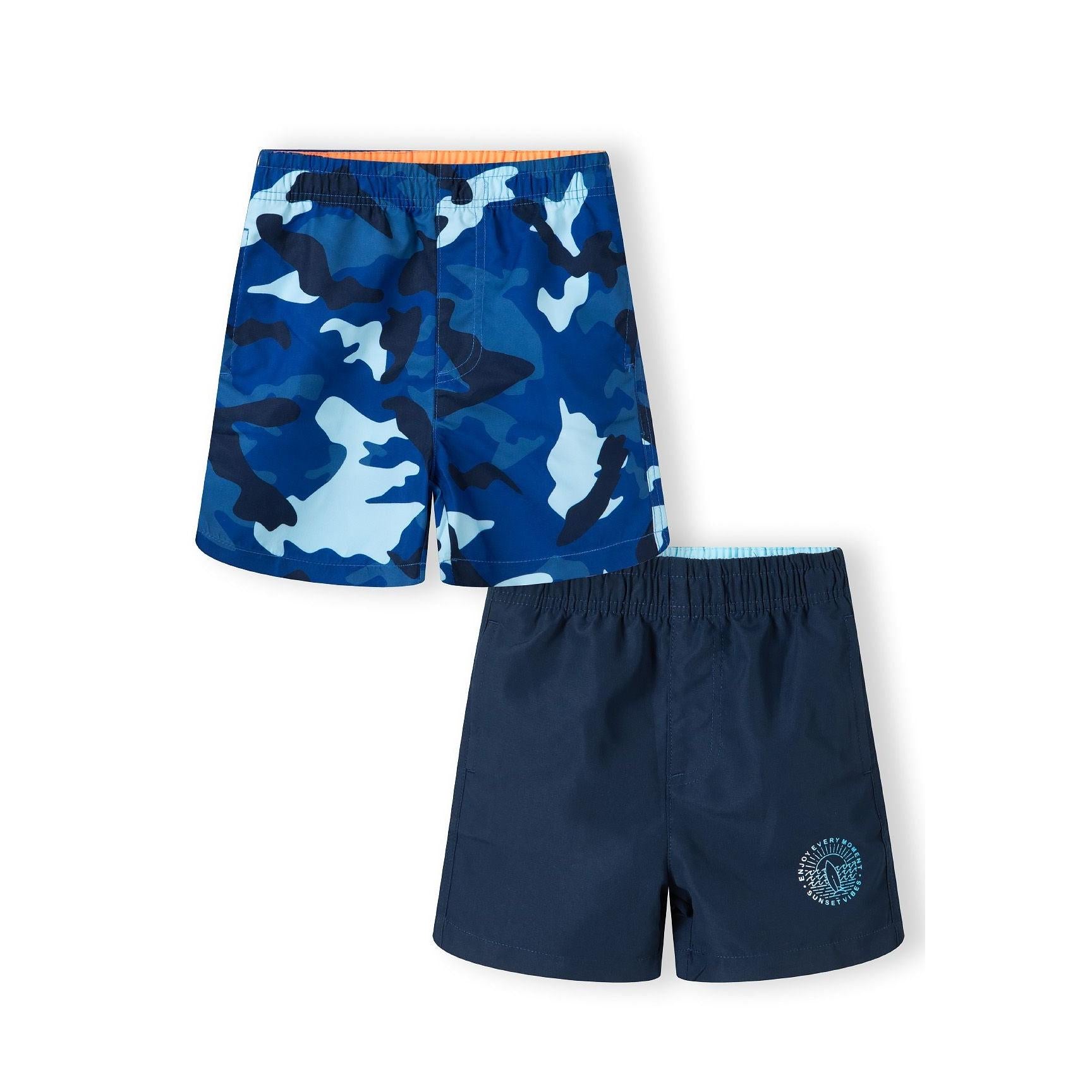 Two navy swim shorts laid flat showing blue camouflage print pair with orange waistband trim and solid navy pair with circular logo on white background