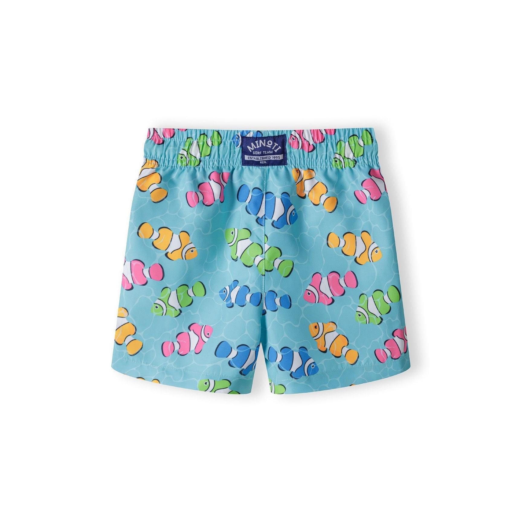 Back view of the same turquoise board shorts showing the Minoti label at the waistband and the all-over clownfish pattern, displayed flat on white background