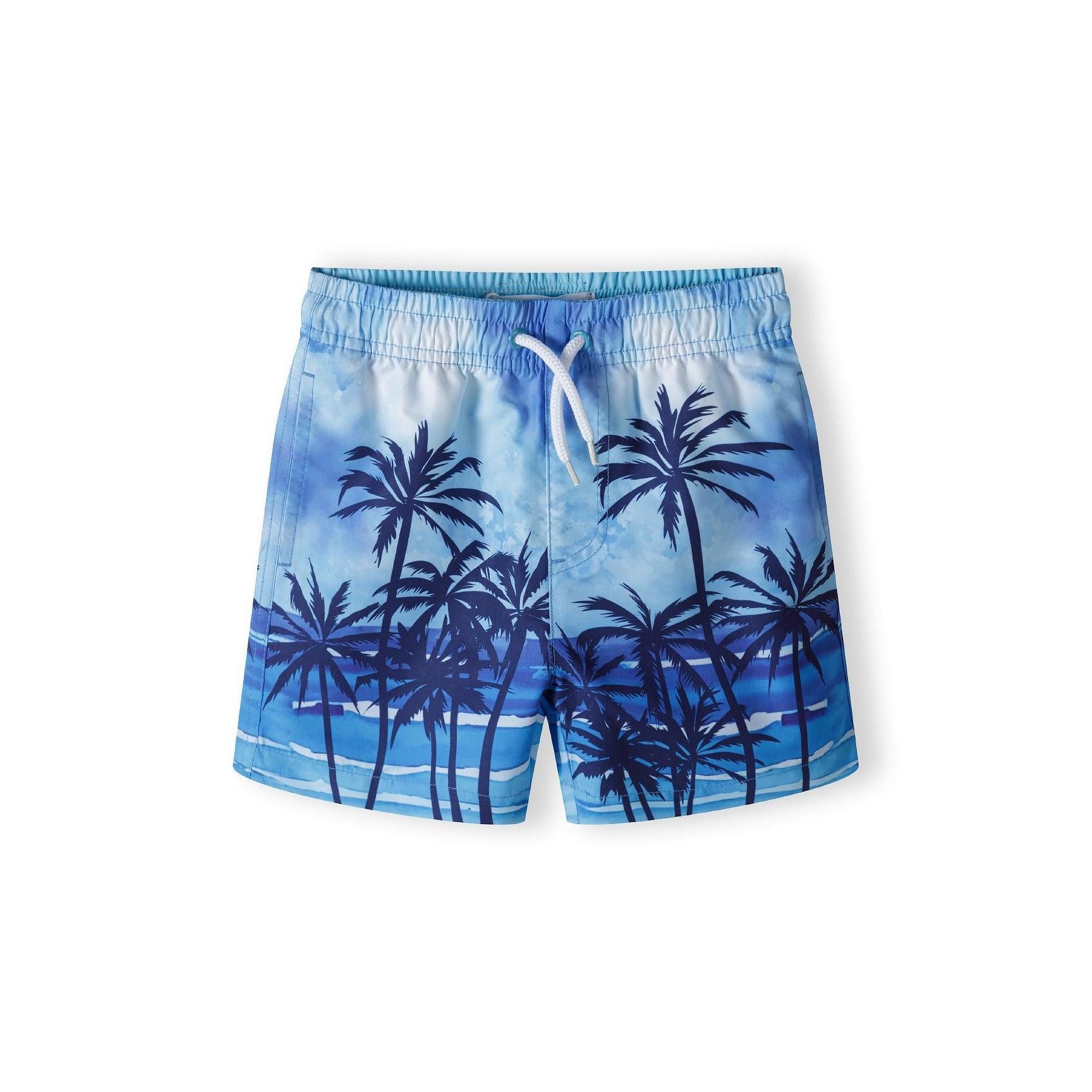 Light blue swim shorts with tropical palm tree print shown flat lay against white background, featuring elastic waistband with white drawstring