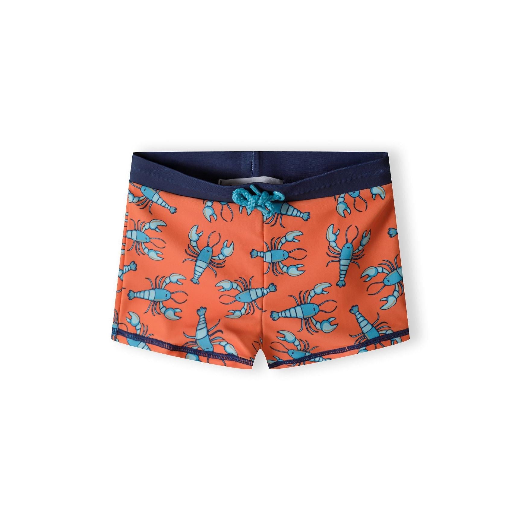 Orange swim shorts with blue lobster print pattern laid flat against white background, showing navy waistband