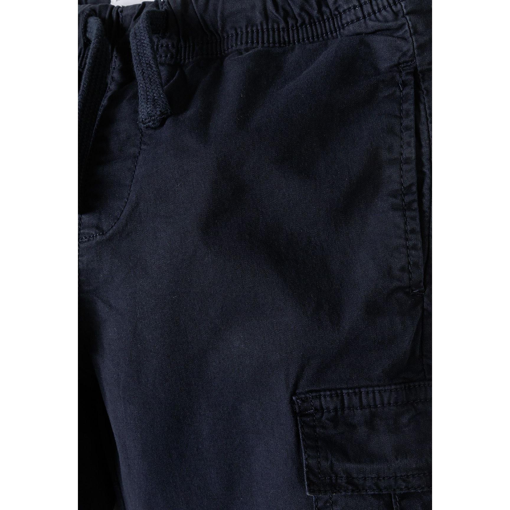 Close-up detail of navy cargo trouser showing cargo pocket construction, elasticated waistband and fabric texture