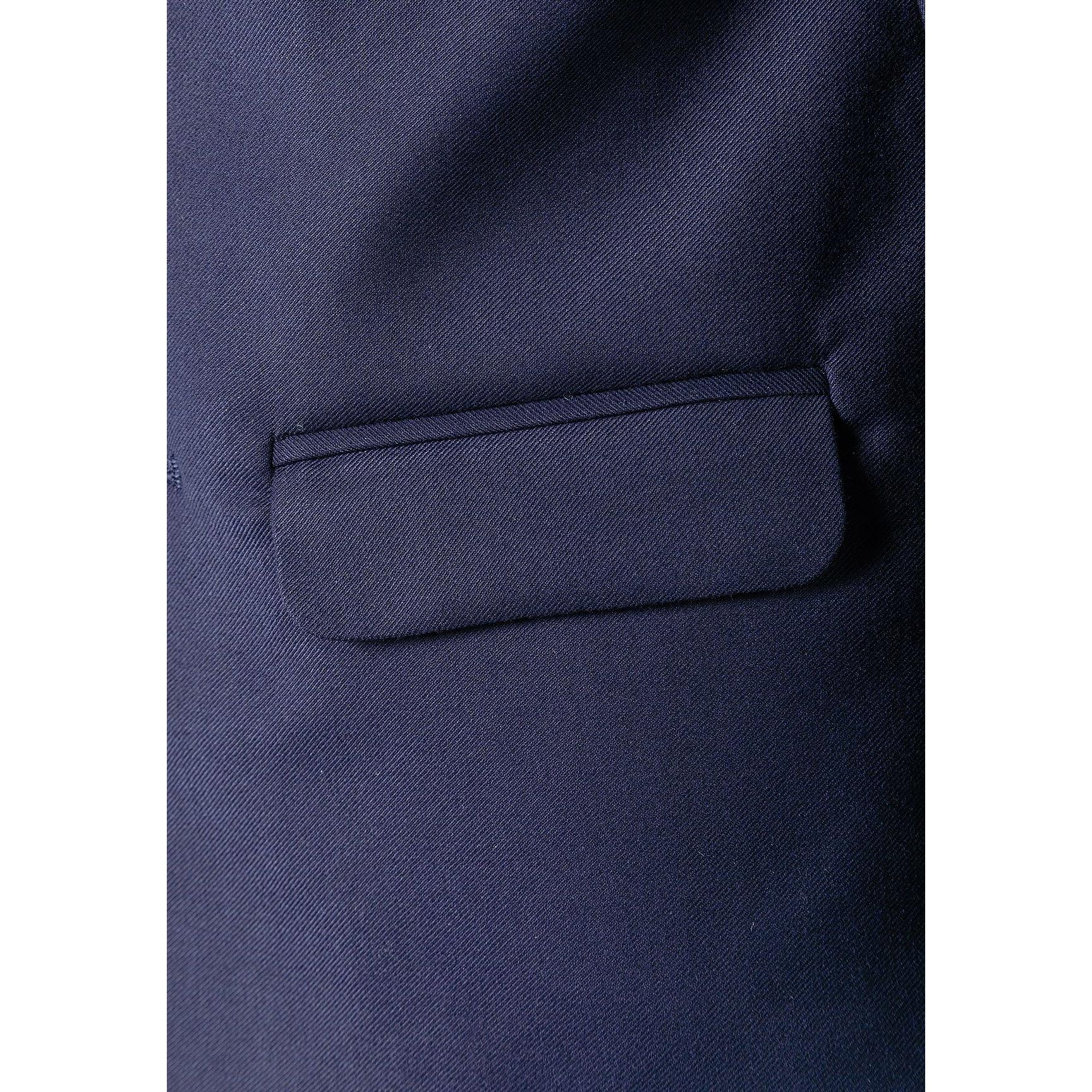 Close-up detail of navy blazer showing chest pocket construction and premium fabric texture