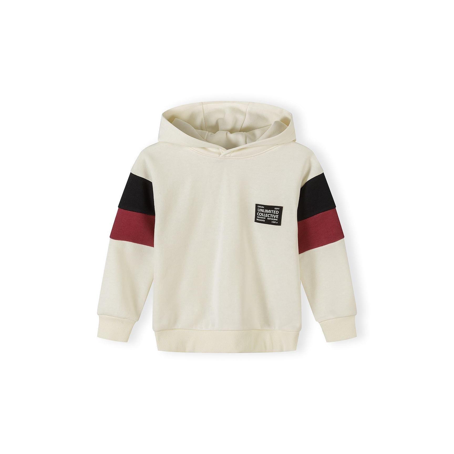 Close-up of cream joggers with black branded patch on thigh, elastic waistband with drawstring, and ribbed cuffs on white background