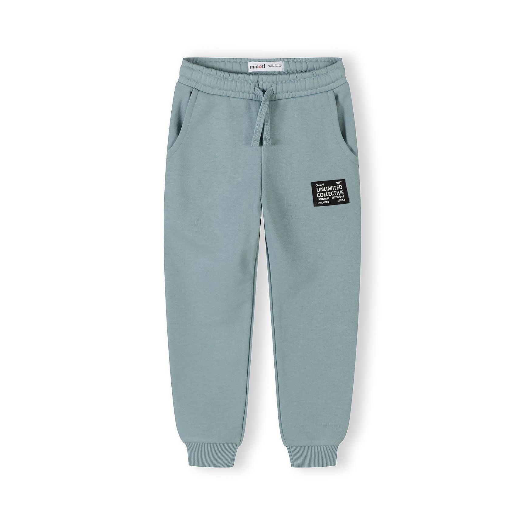 Sage blue joggers with elasticated waistband, drawstring and branded 'Unlimited Collective' patch on left leg, shown flat against white background