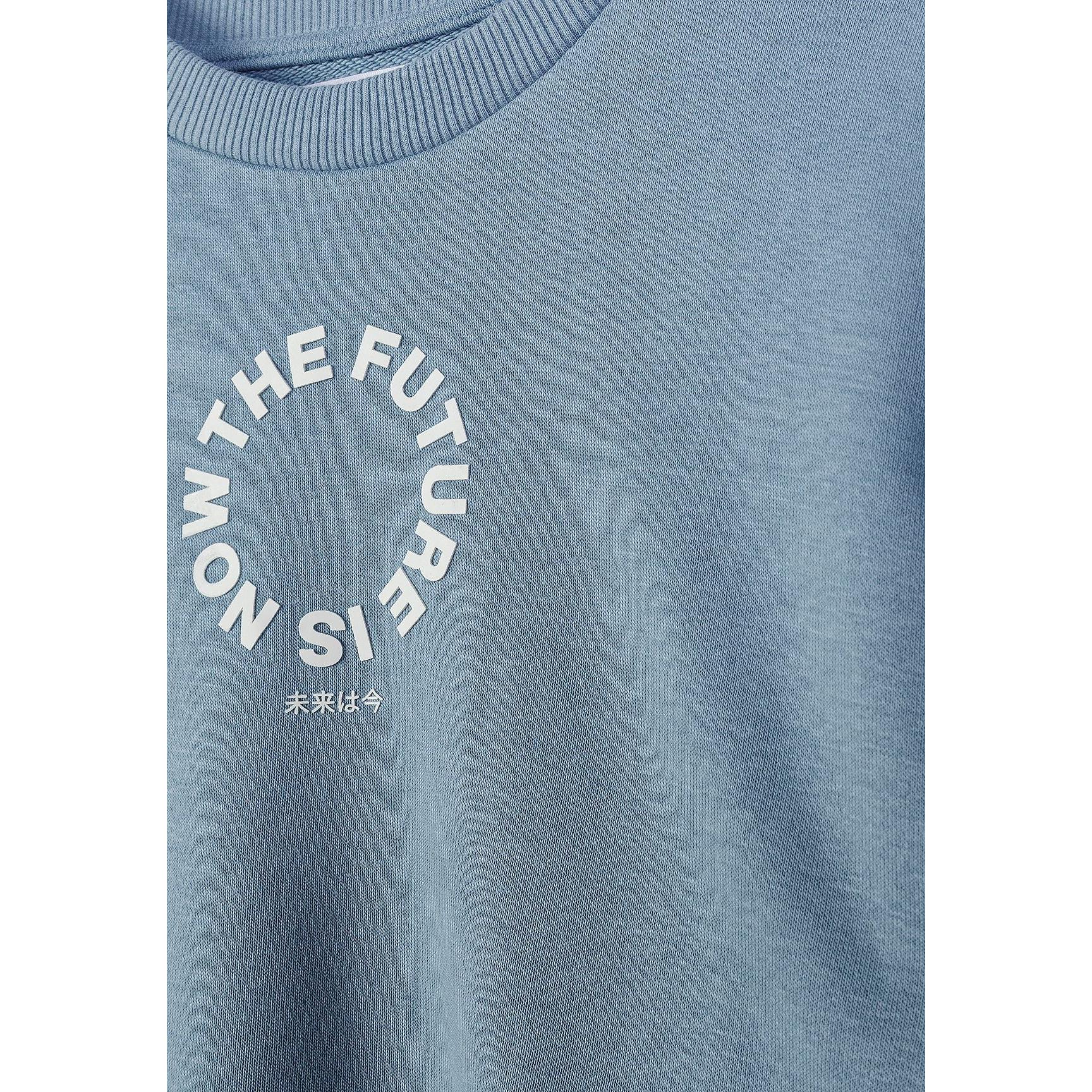 Close-up detail of front chest area showing circular 'The Future is Now' text print with Japanese characters on blue grey fabric