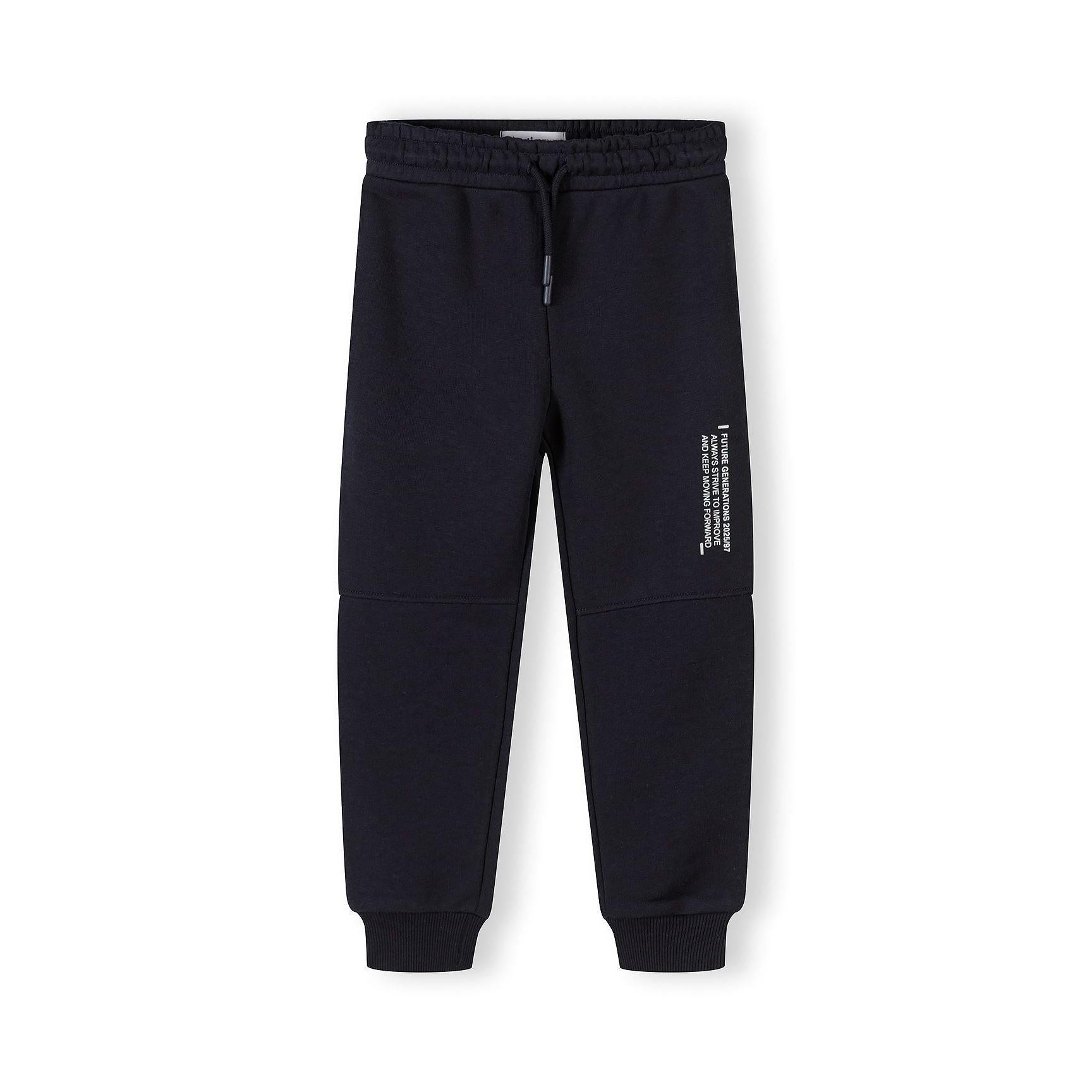 Close-up front view of black joggers showing elasticated waistband with drawstring and text detail on leg