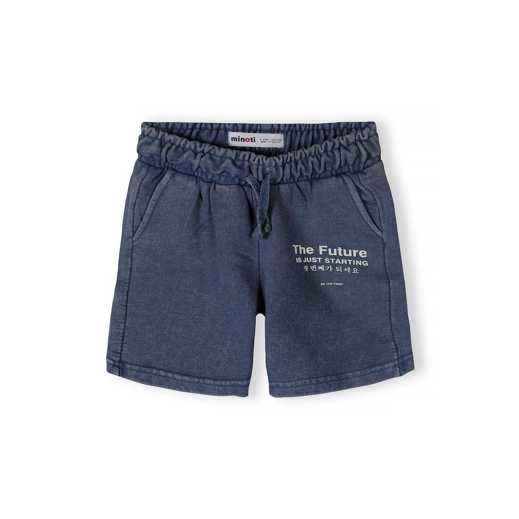 Close-up detail of blue acid wash shorts waistband showing Minoti label and 'The Future is Just Starting' text with Korean translation