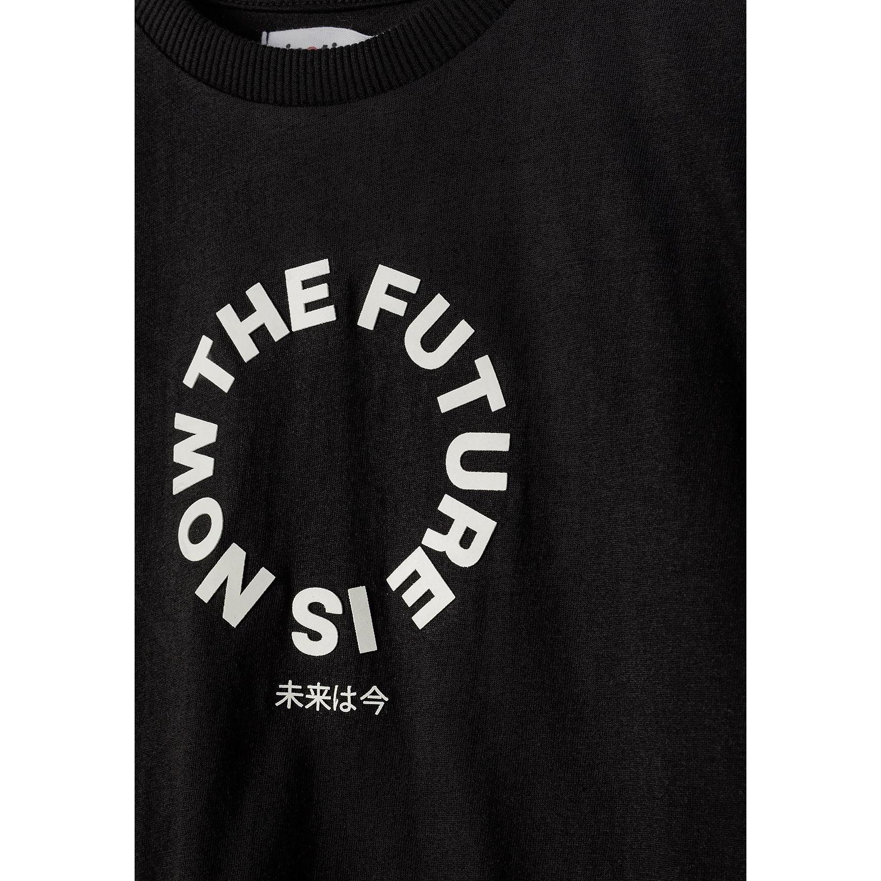 Close-up front view of black t-shirt showing detailed The Future is Now circular white text print with Japanese characters below