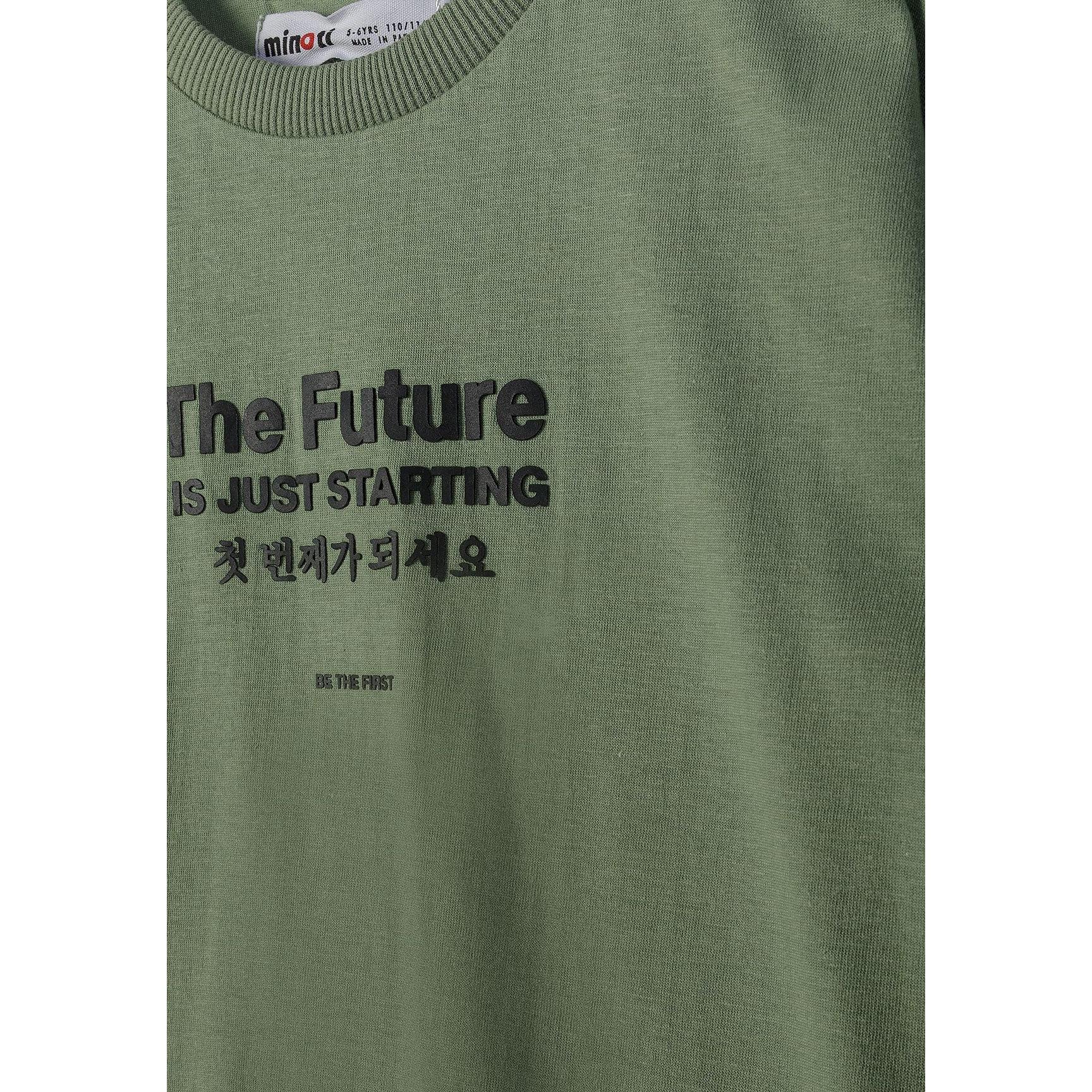 Close-up detail of olive green t-shirt fabric showing 'The Future Is Just Starting' print with Korean text underneath and Minoti label at neckline