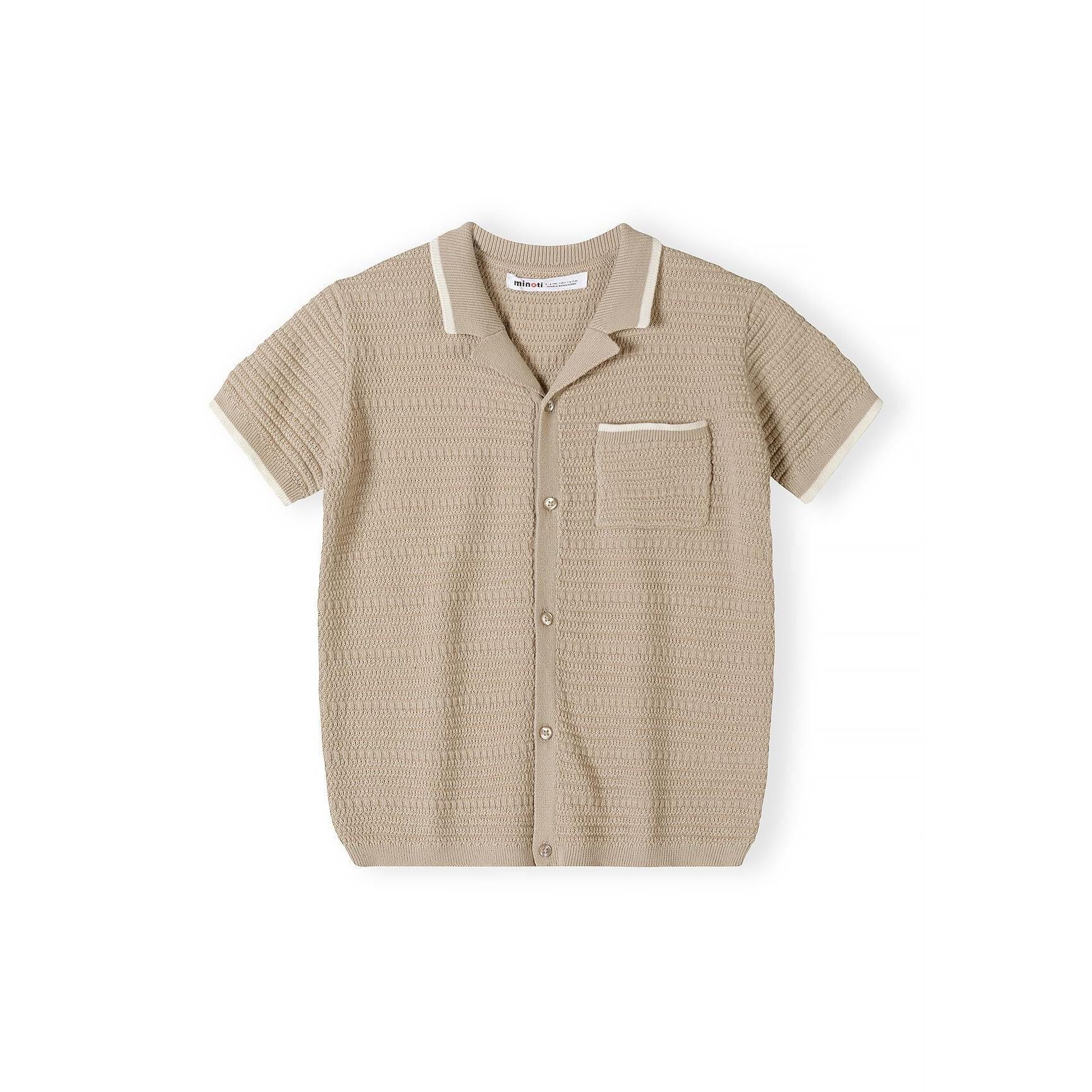 Close-up detail of beige polo shirt showing Minoti label, button placket, chest pocket and herringbone knit texture