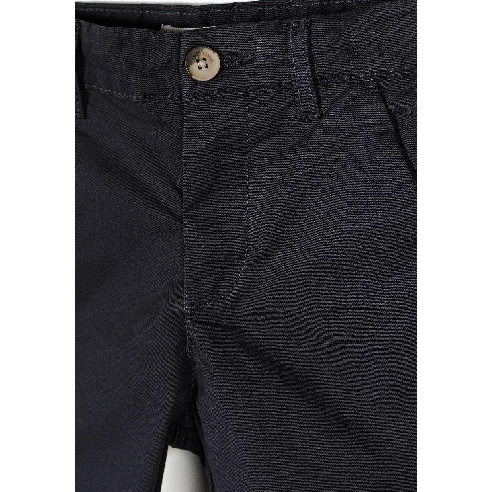 Close-up detail of navy chino shorts showing waistband construction, brown button closure, belt loop and side pocket opening