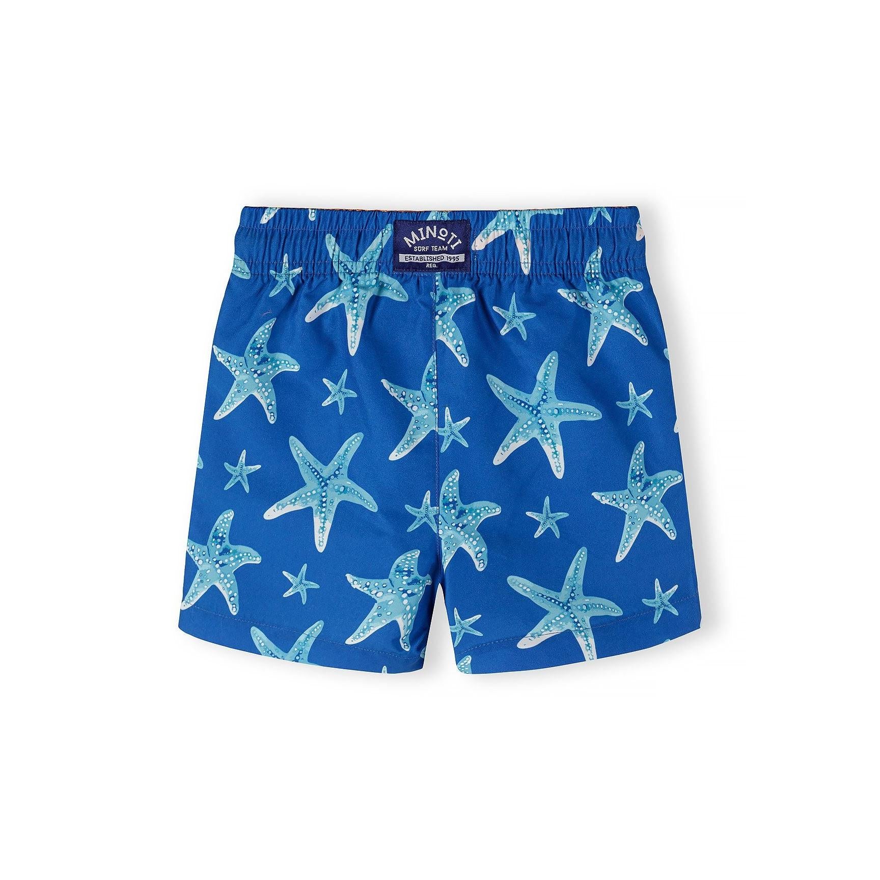 Close-up detail of swimming shorts waistband showing orange elasticated fabric with white drawstring and blue wavy stripe pattern below