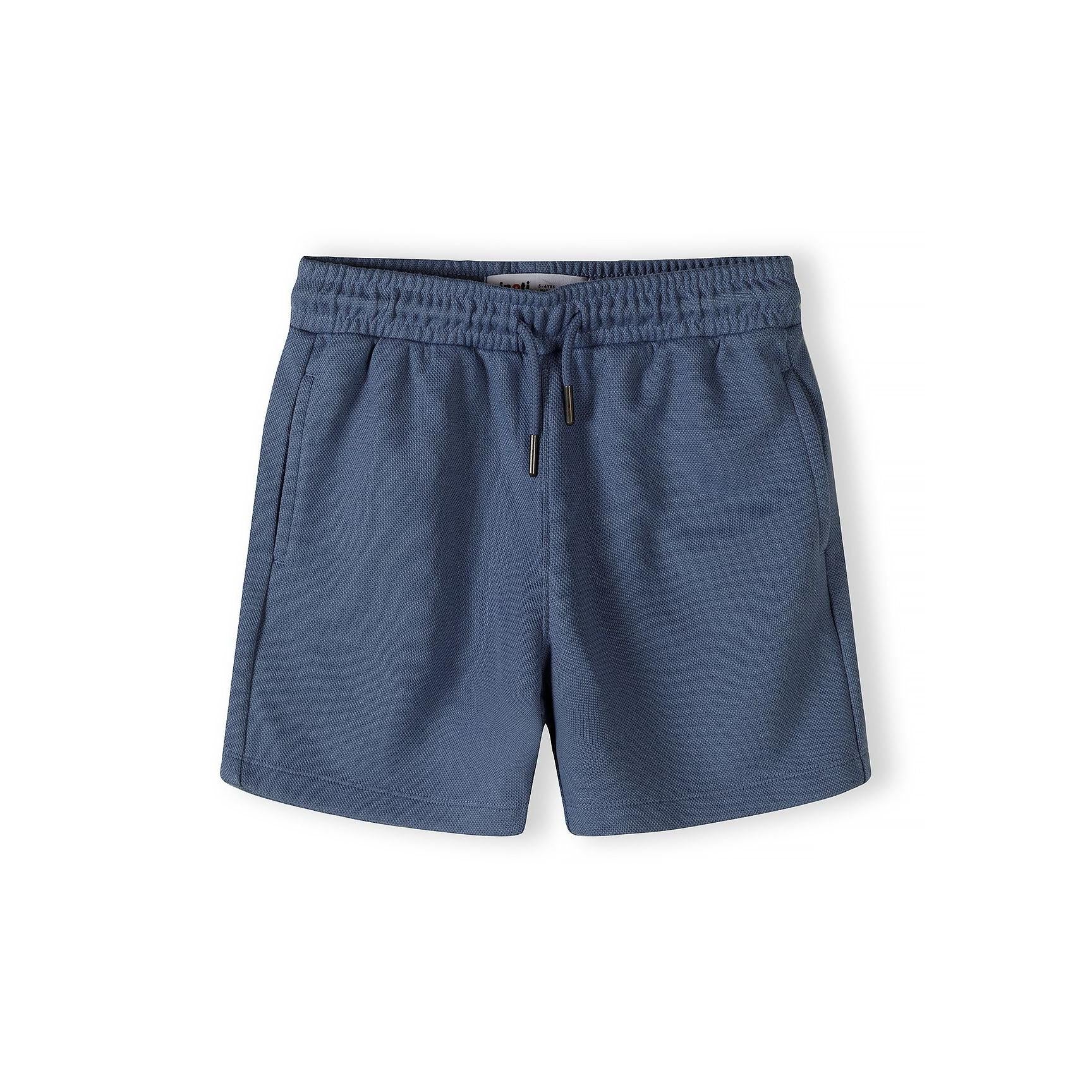 Close-up detail of navy blue pique polo shirt showing Minoti label, zip fastening and colour-block design with textured fabric