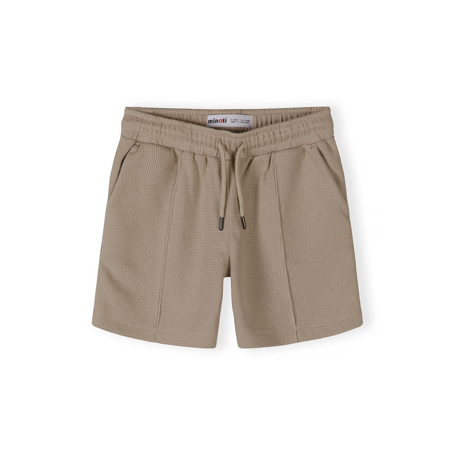 Close-up detail of taupe waffle cotton shirt showing Minoti label, button placket and textured fabric weave