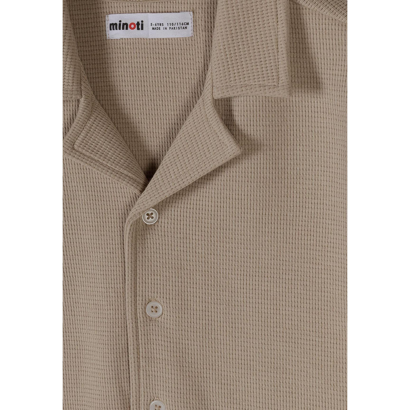 Close-up detail of taupe waffle cotton shirt showing Minoti label, button placket and textured fabric weave