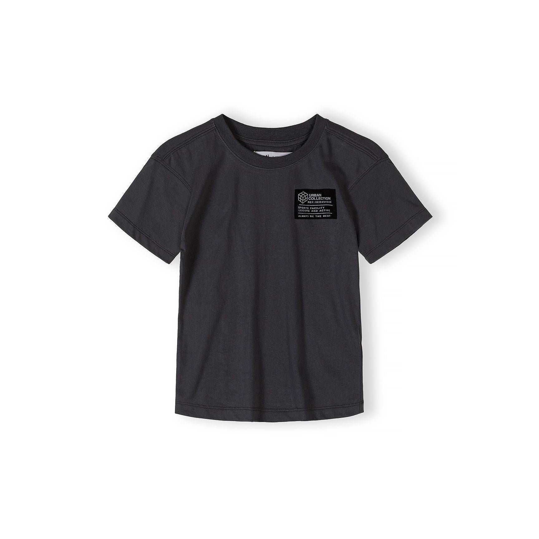 Close-up detail of urban collection patch on grey t-shirt featuring geometric cube logo and text