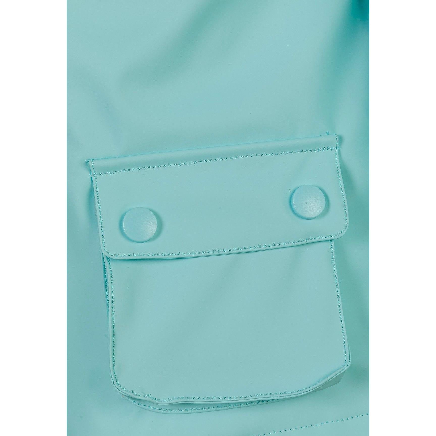 Close-up detail of mint green rain jacket side pocket with button flap closure, showing the waterproof fabric texture and stitching details