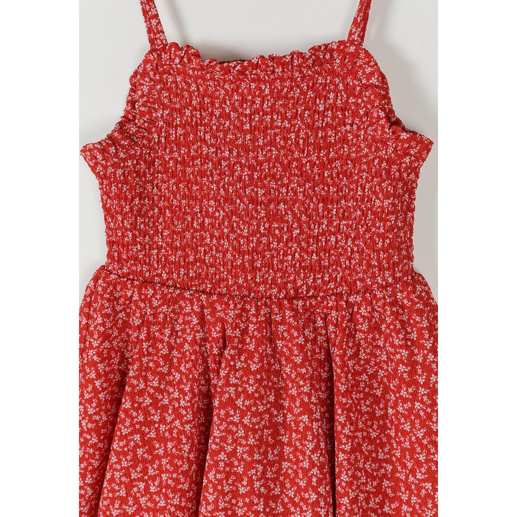 Close-up detail of red dress showing shirred bodice texture with white floral pattern and adjustable strap construction
