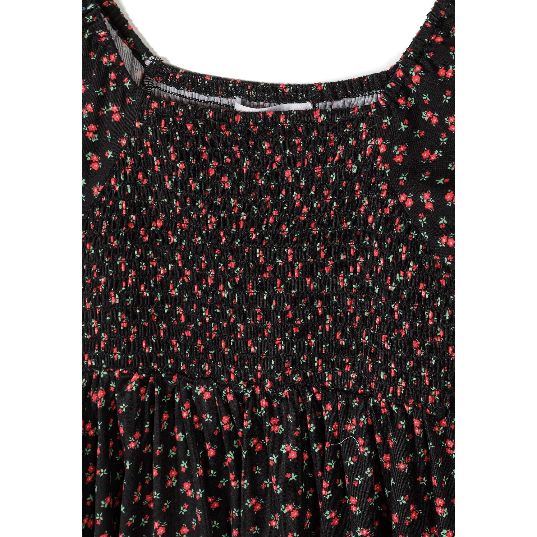 Close-up detail of black dress showing shirred bodice construction with elastic gathering and delicate floral print pattern