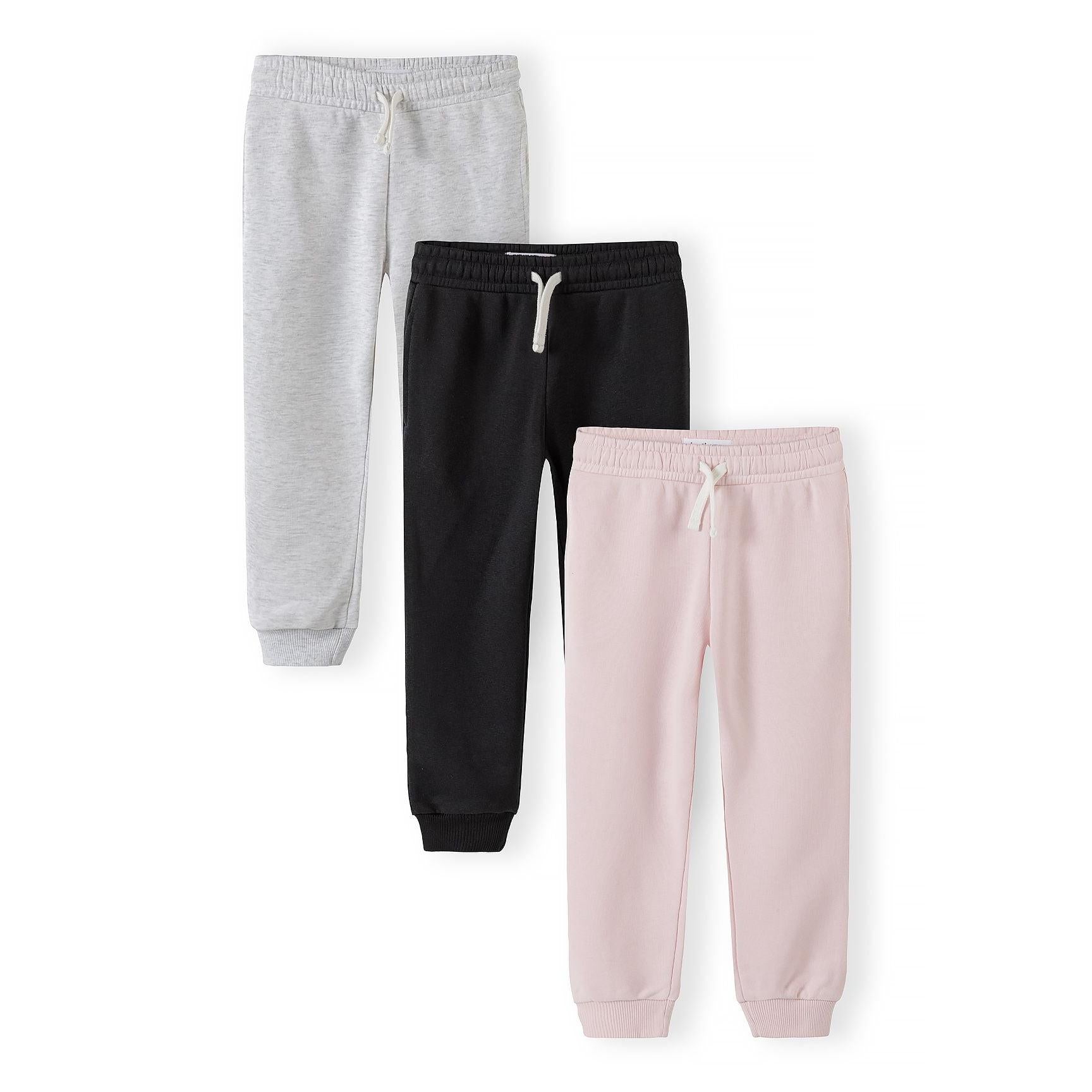 Three children's joggers laid flat - light pink, grey, and black joggers with white drawstrings and ribbed cuffs on white background