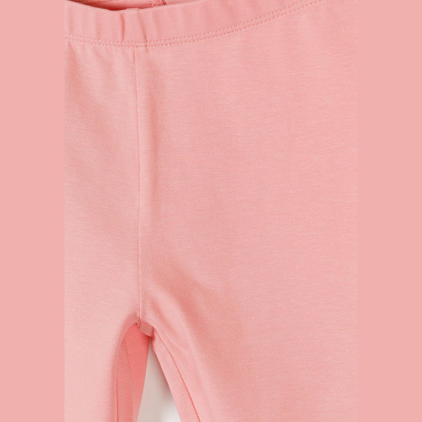 Close up detail of coral pink leggings showing soft fabric texture and comfortable elastic waistband construction
