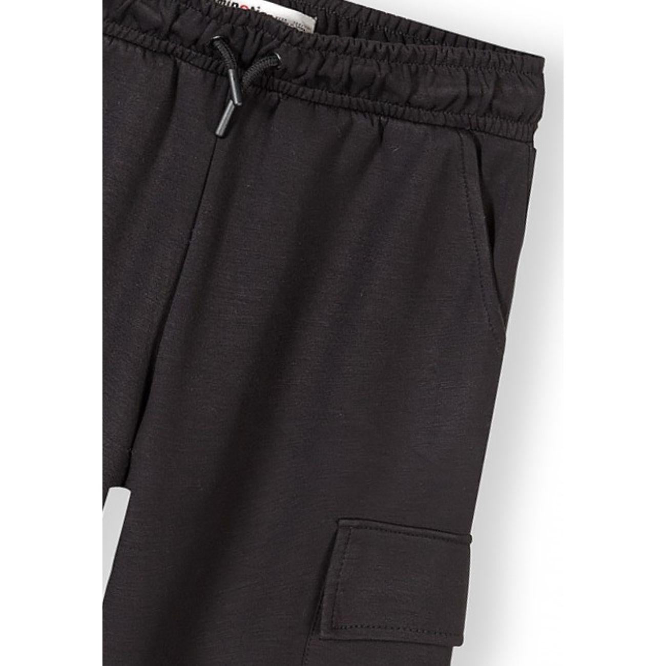 Close-up detail of black joggers showing elasticated waistband with black drawstring and cargo pocket with flap closure